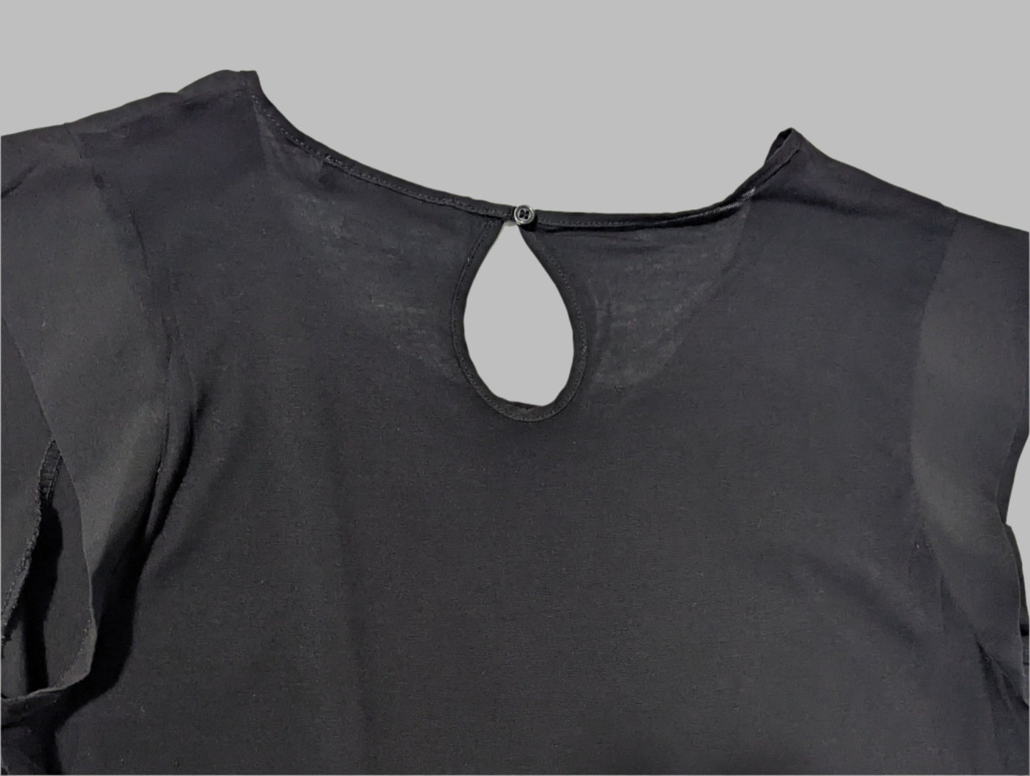 rear view of a black sleeveless French Connection blouse on a hanger featuring a round neck and elegant front keyhole cutout detail.