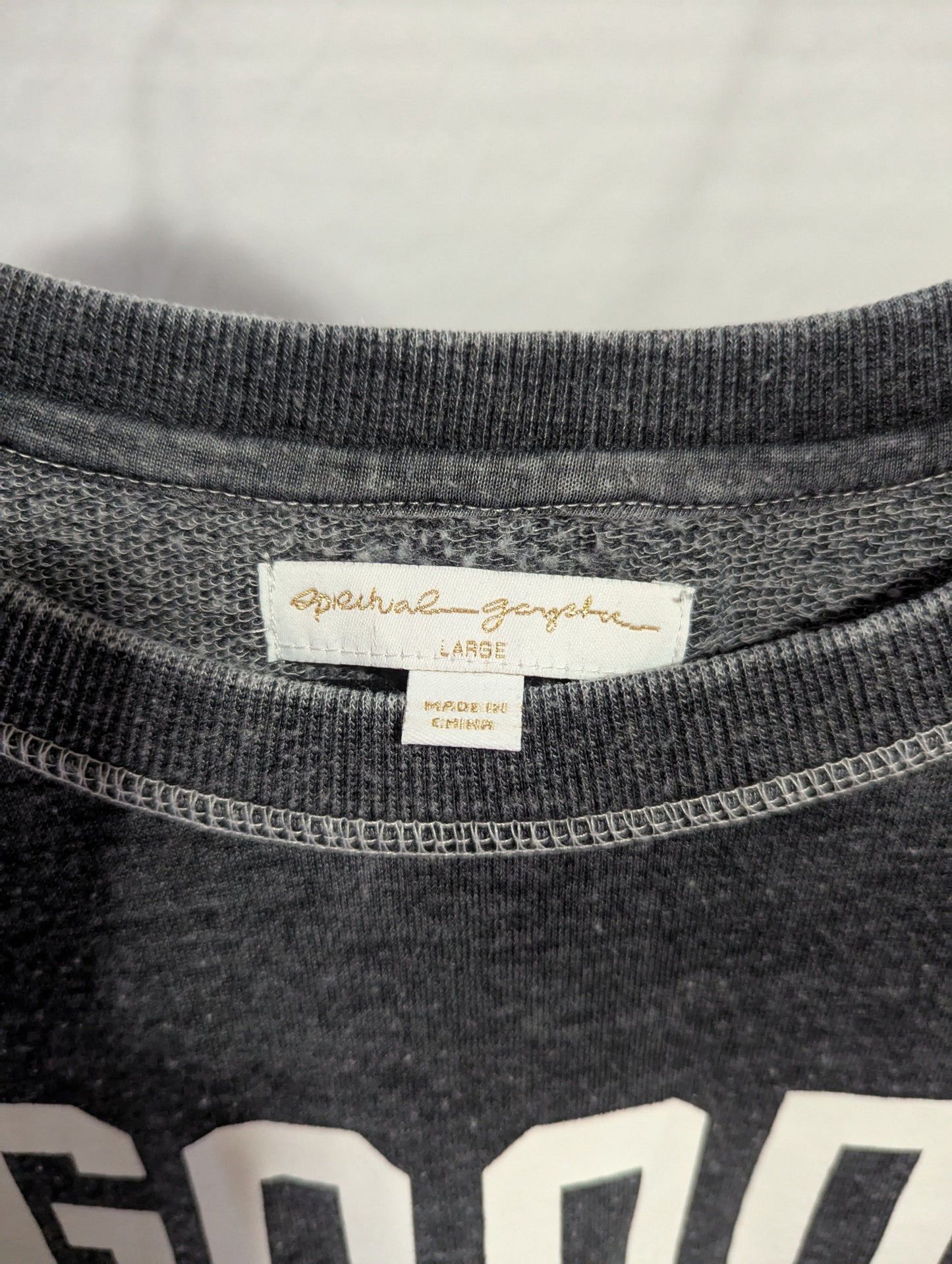 Close-up detail of the crew neckline and authentic interior Spiritual Gangster brand logo label inside the collar