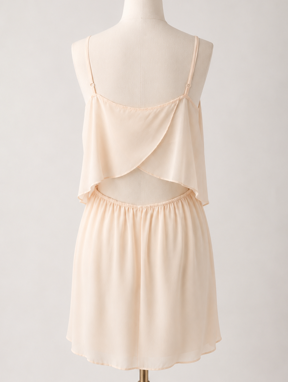 BCBG light peach spaghetti strap layered mini dress with sheer cutout detail and hidden pockets displayed on mannequin rear view