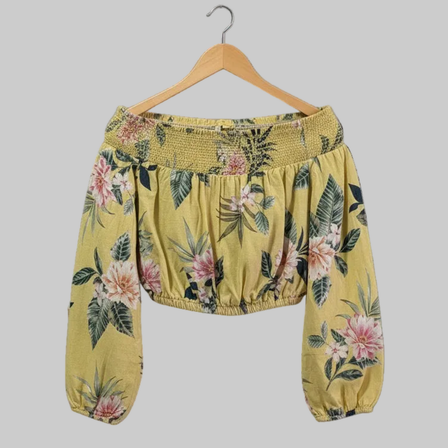 Close-up view of the bodice of a yellow floral Guess crop top, highlighting the gathered elastic, off-the-shoulder neckline, and the lightweight linen-rayon blend fabric texture.