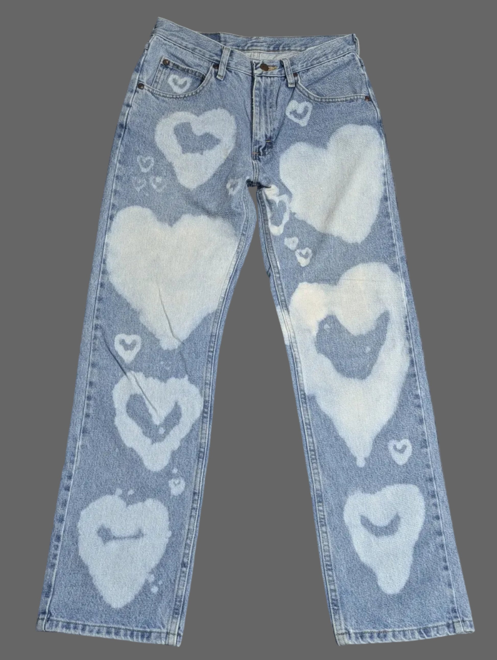 Front view of light wash vintage Wrangler straight leg denim jeans with a custom white bleached heart pattern down both legs.