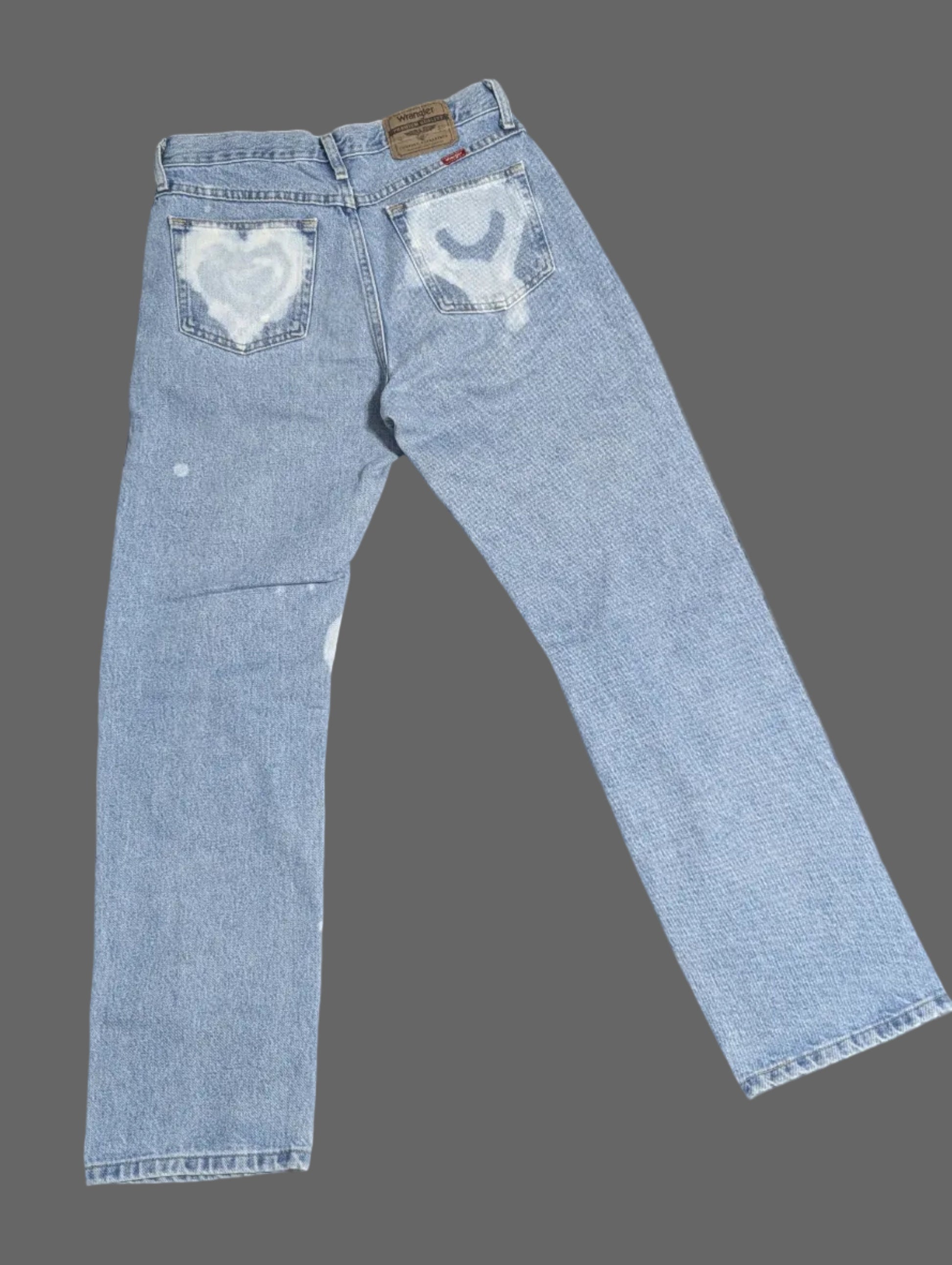 Rear view of light wash vintage Wrangler straight leg denim jeans with a custom white bleached heart pattern down both legs.