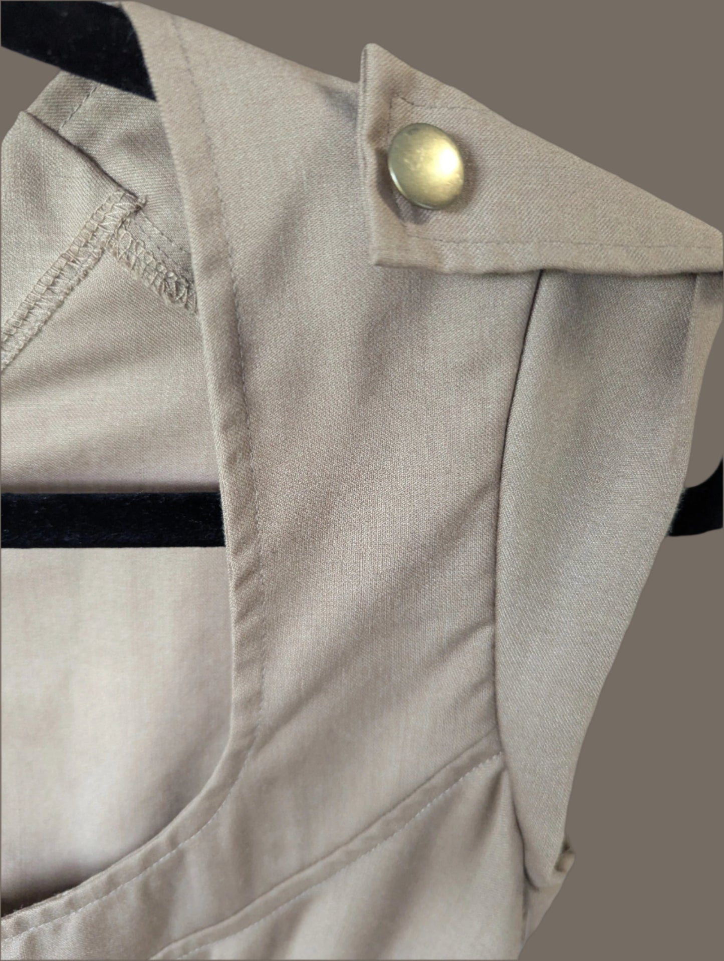Detailed macro close-up of the premium khaki wool blend fabric and a decorative gold metallic button on the shoulder of the Allison Wonderland midi dress.