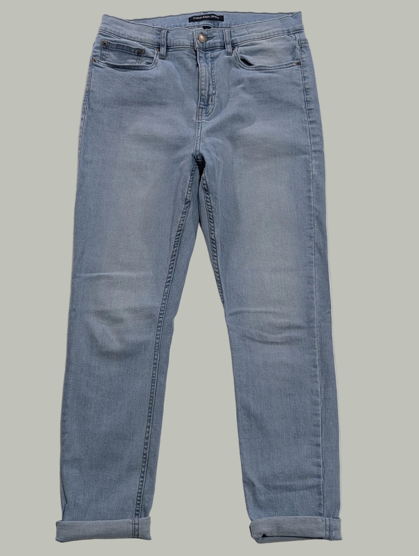 Front full-length view of light wash blue Calvin Klein super skinny jeans with folded cuffed hems, laying flat