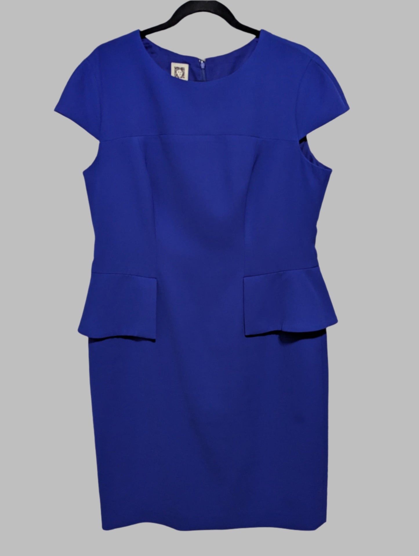 Front view of a purple Anne Klein short sleeve peplum midi dress hanging on a hanger.