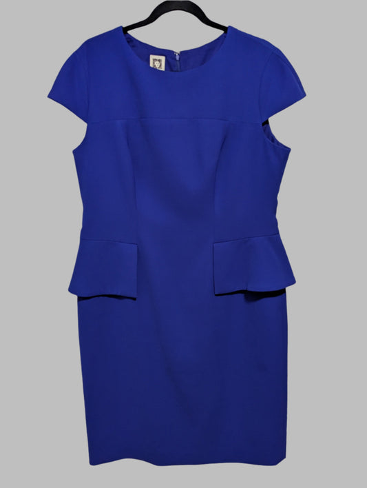 Front view of a purple Anne Klein short sleeve peplum midi dress hanging on a hanger.