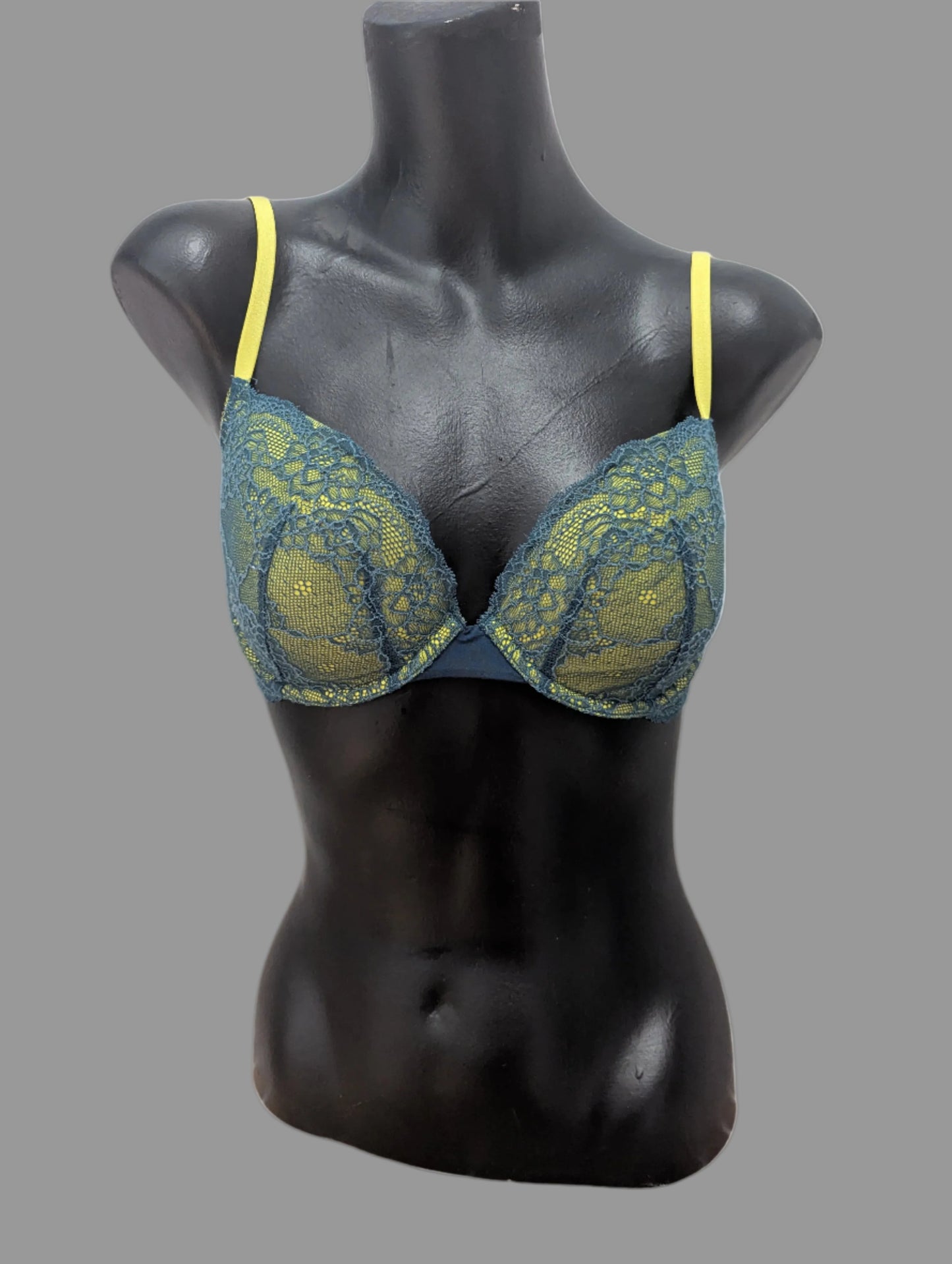 Front view of a lime green and teal lace BCBG lightly padded underwire demi bra on a black mannequin.