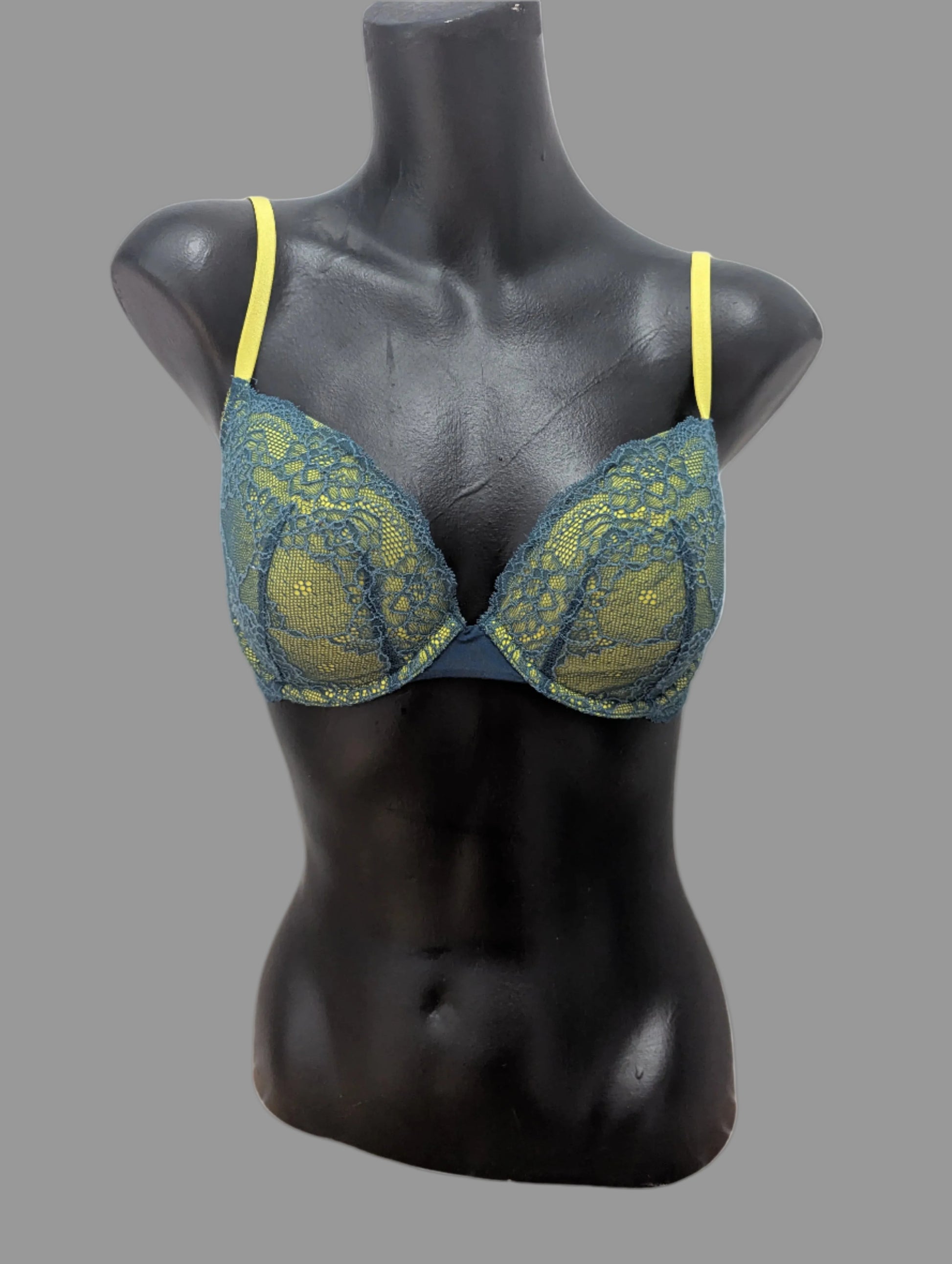 Front view of a lime green and teal lace BCBG lightly padded underwire demi bra on a black mannequin.