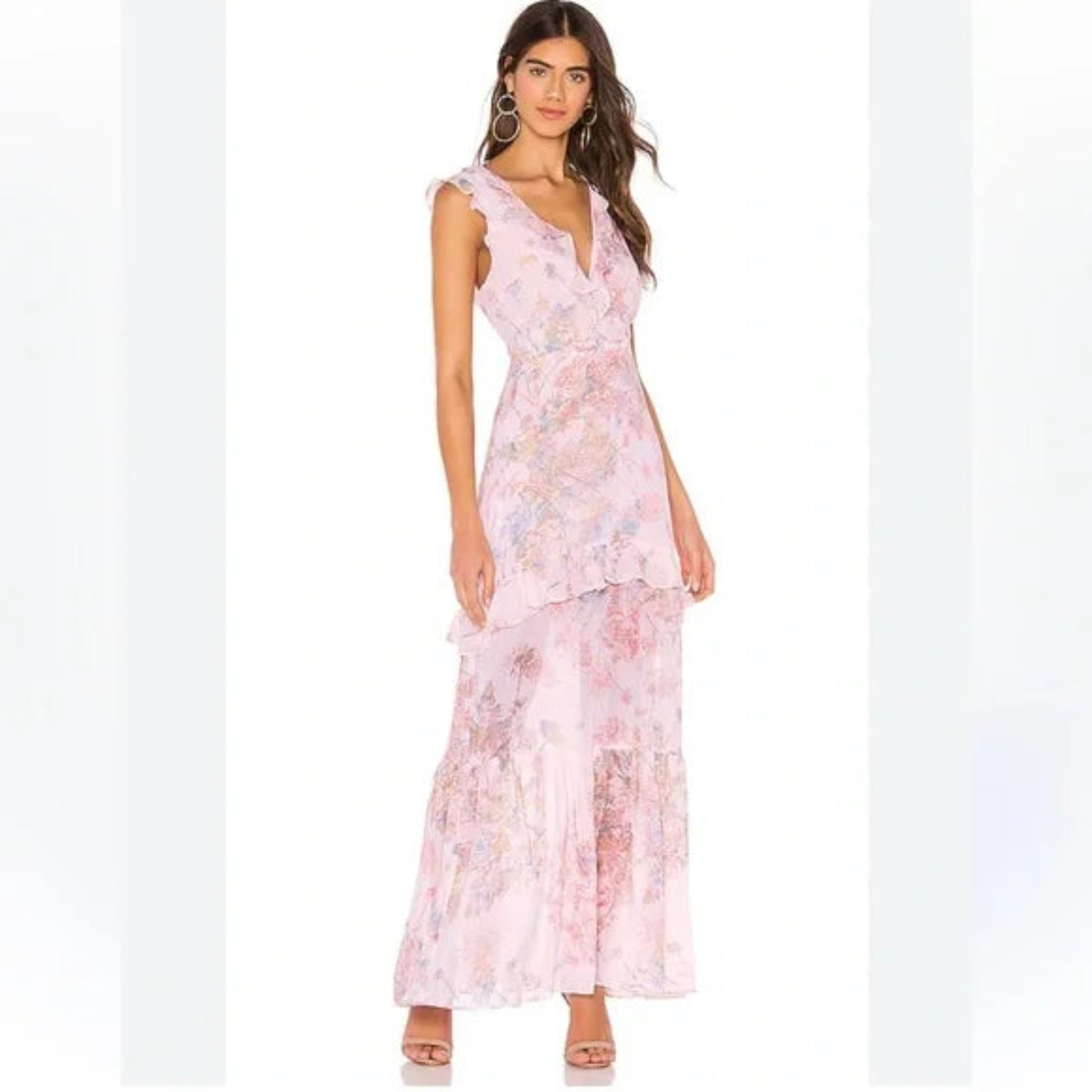 Full-length view of a model wearing a pink BCBGMAXAZRIA sleeveless maxi dress with a vibrant floral pattern and ruffled tiered skirt.