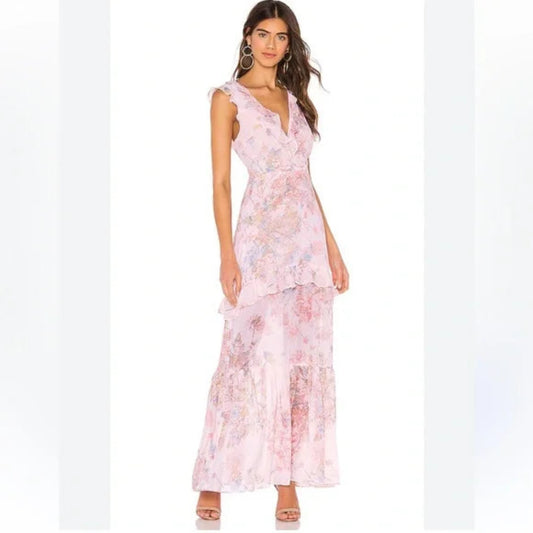 Full-length view of a model wearing a pink BCBGMAXAZRIA sleeveless maxi dress with a vibrant floral pattern and ruffled tiered skirt.
