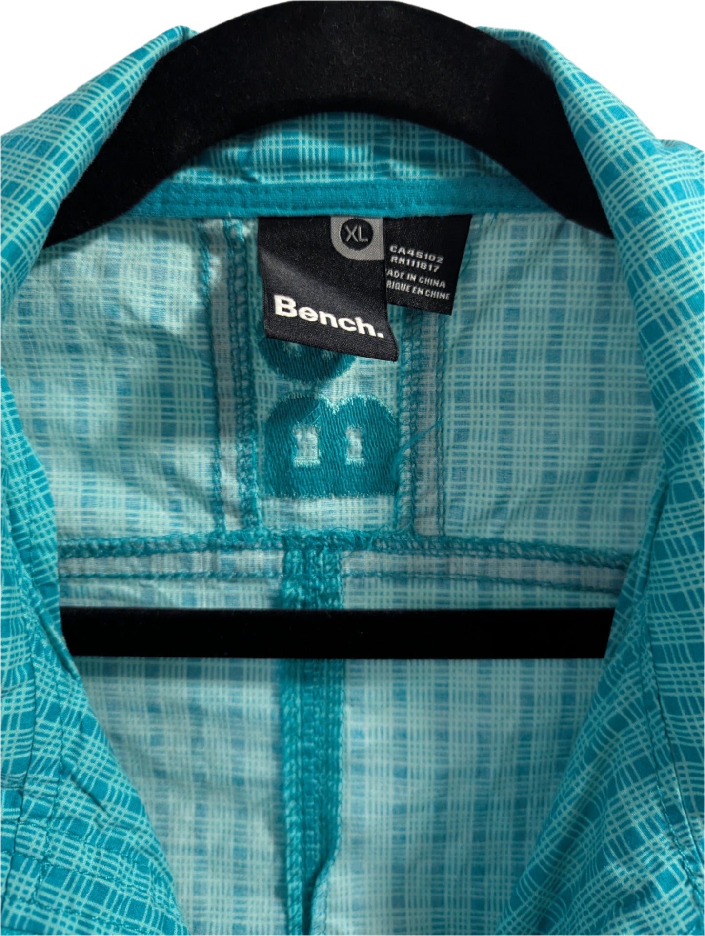 Close-up detail of the collar, neckline, and front zipper closure on the teal Bench lightweight jacket.