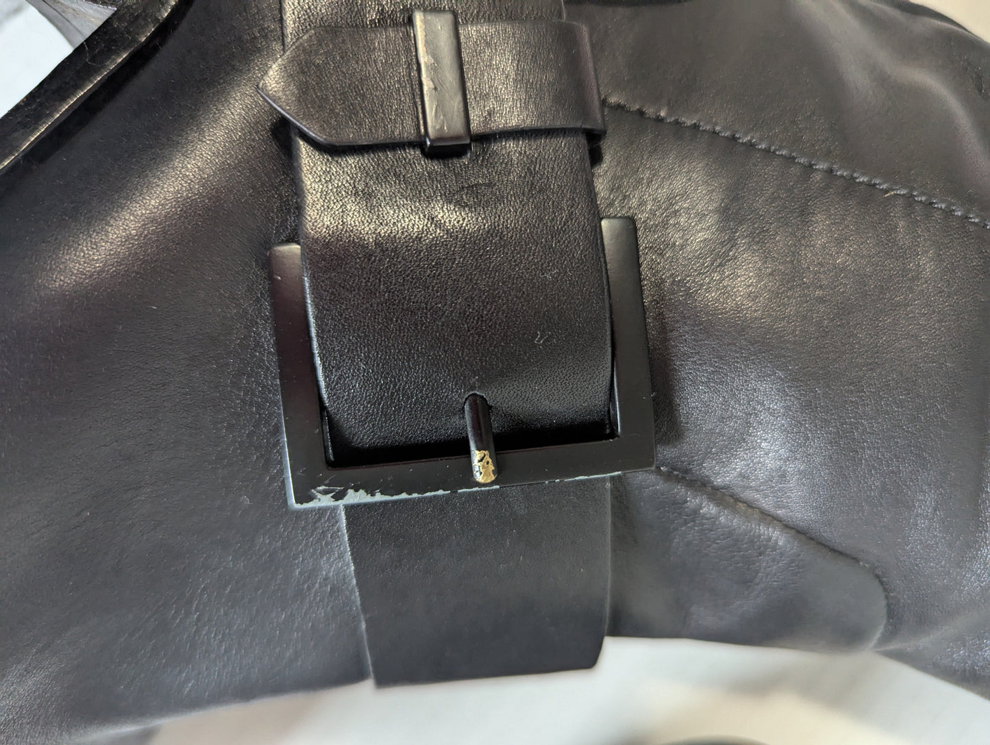 Close-up detail of the premium silver double buckle hardware accents on the ankle of the black leather boot