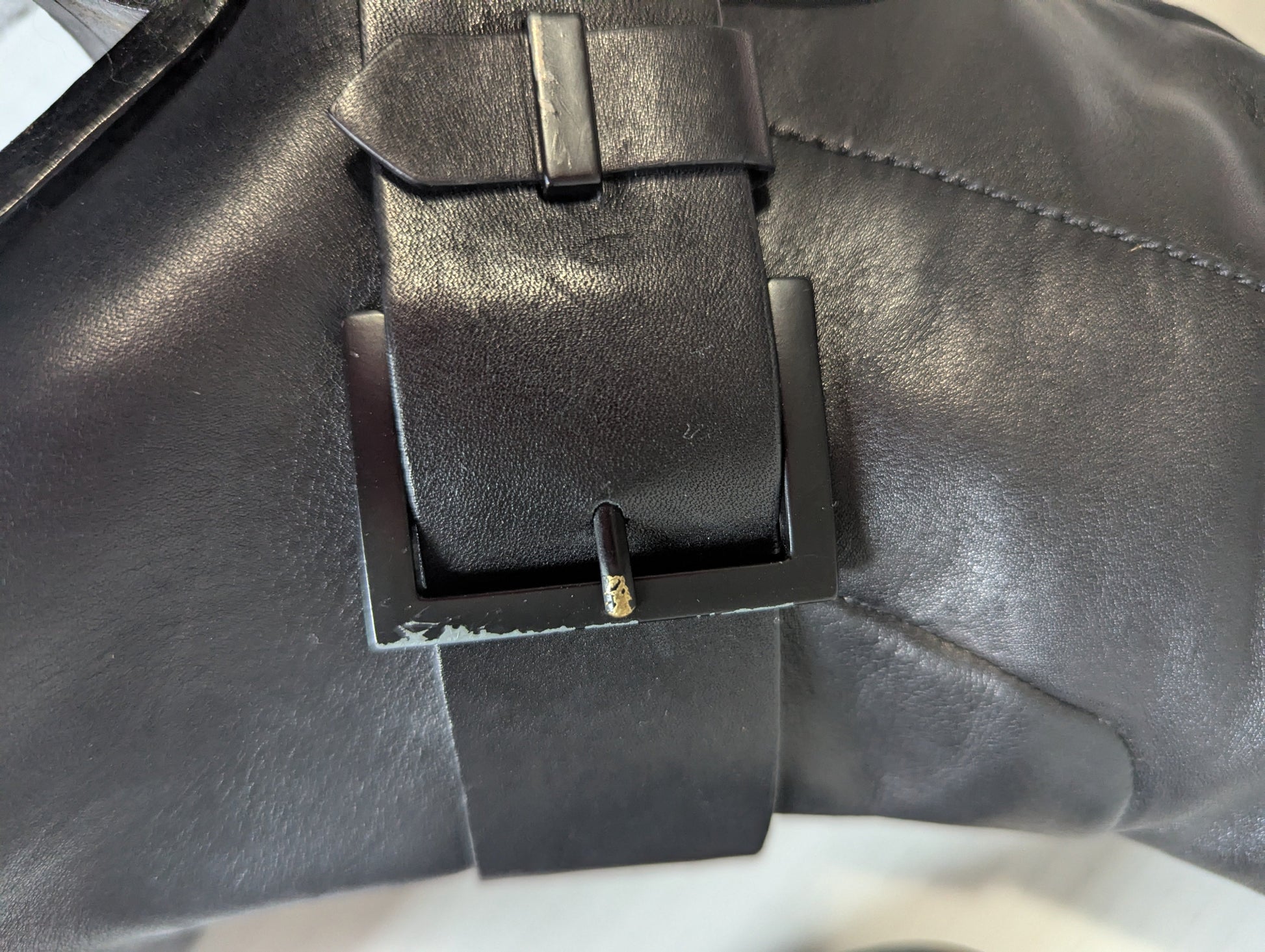 Close-up detail of the premium silver double buckle hardware accents on the ankle of the black leather boot