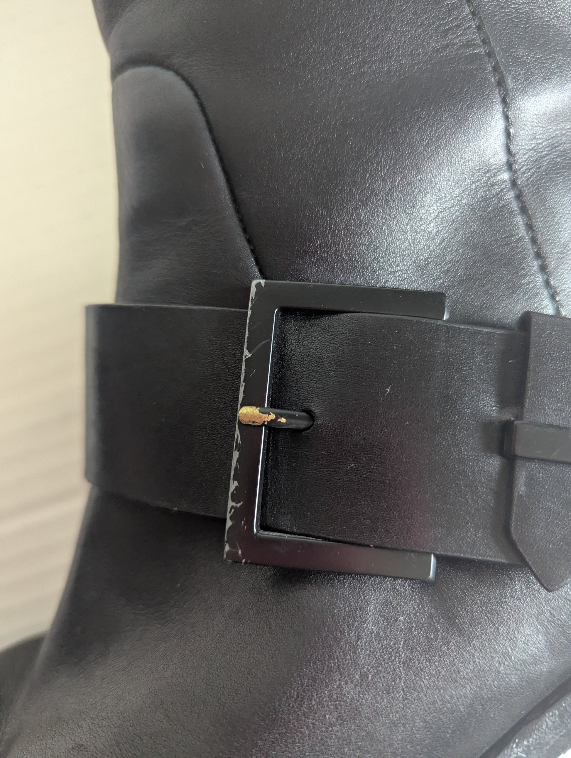 Close-up detail of the premium silver double buckle hardware accents on the ankle of the black leather boot.