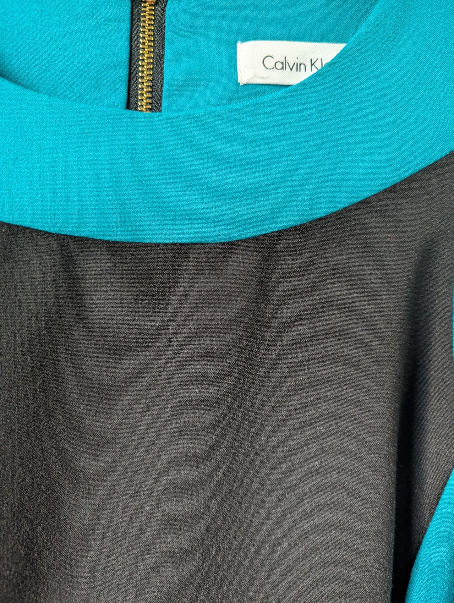 Detailed close-up of the luxury gold zipper pull and the structured poly-rayon-spandex blend fabric texture.