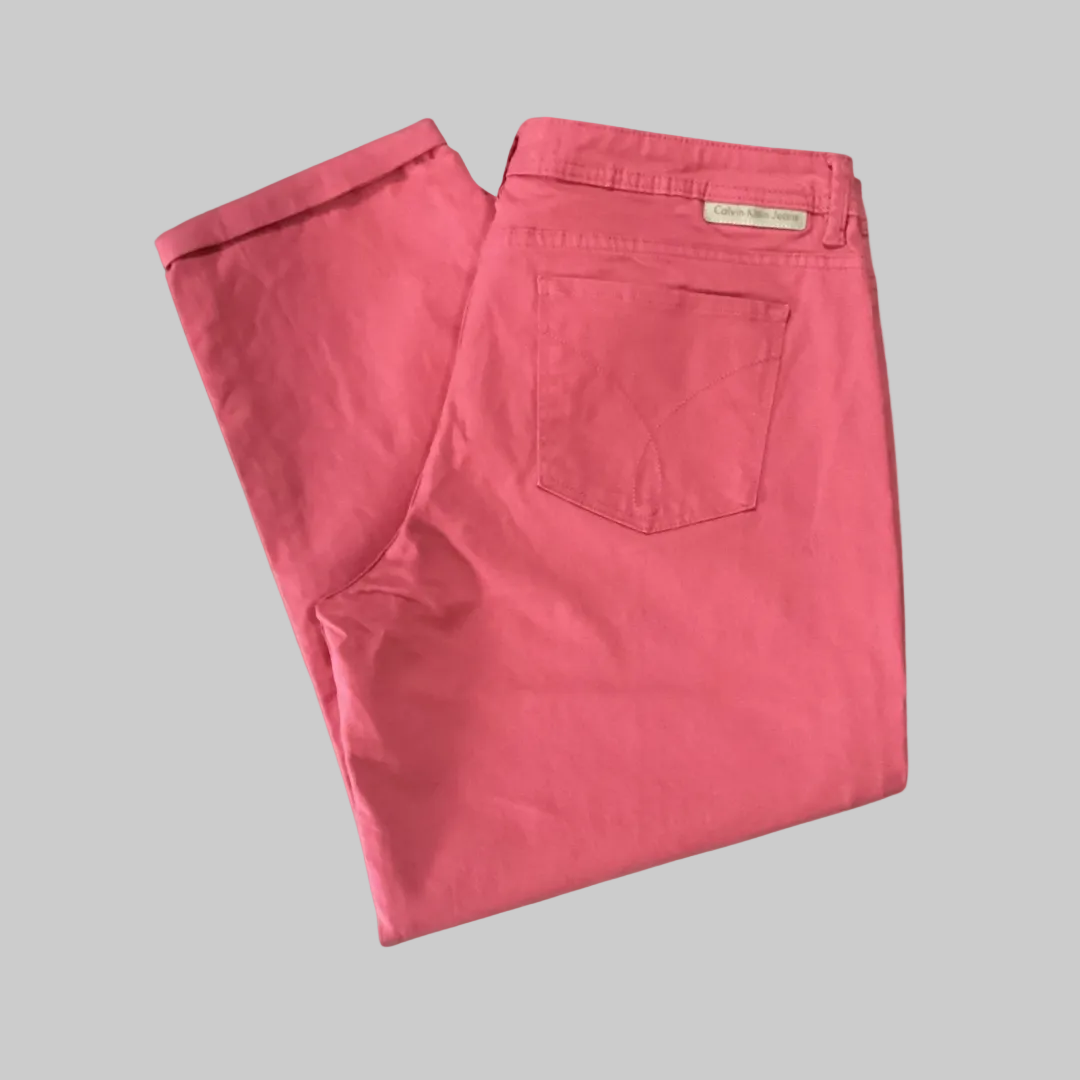 Folded flat lay view of the salmon pink Calvin Klein cropped straight leg jeans, highlighting the clean, like-new fabric condition.