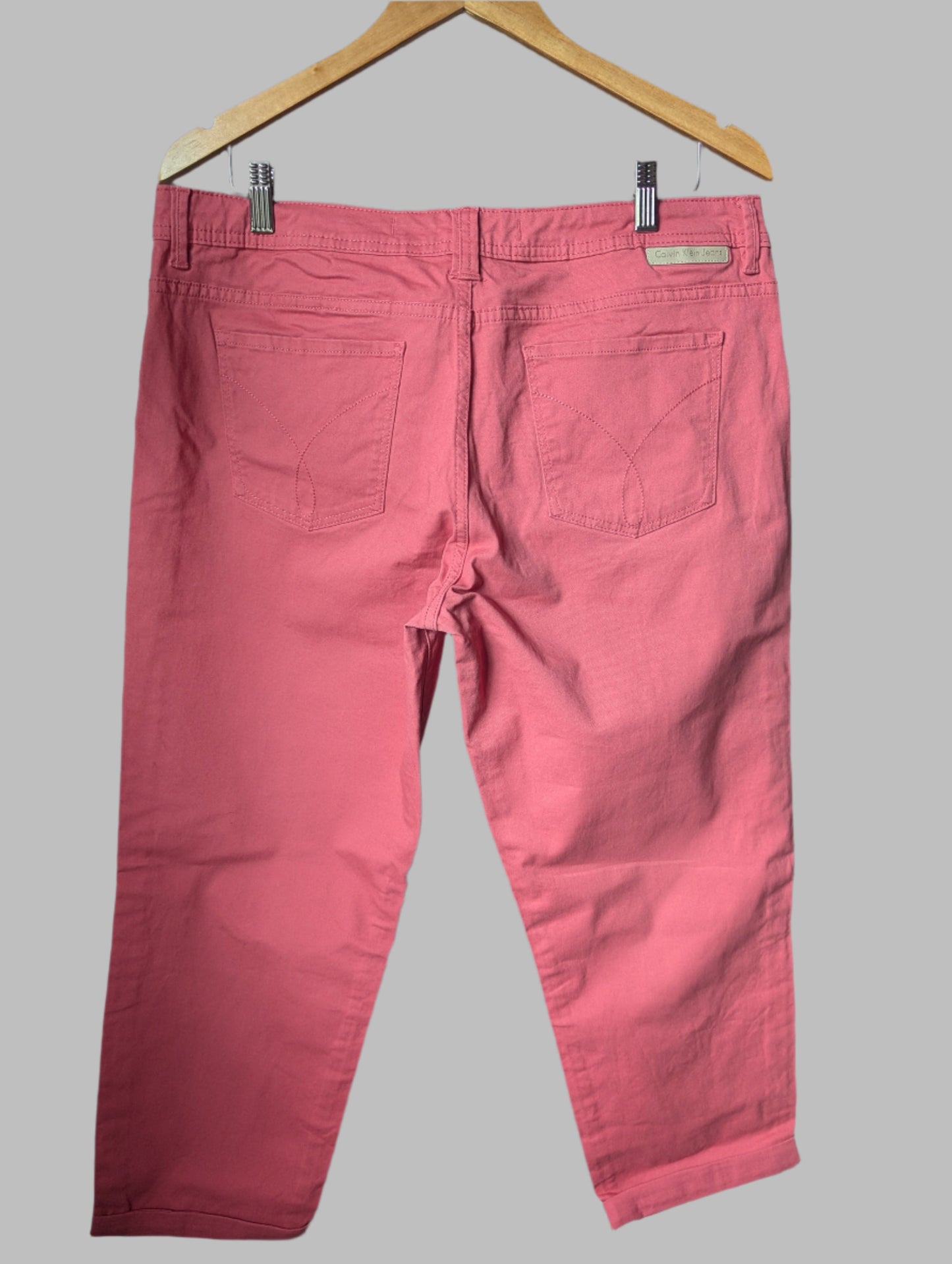 Close-up back view of the salmon pink Calvin Klein jeans, showcasing the classic pocket stitching and high-waisted fit.