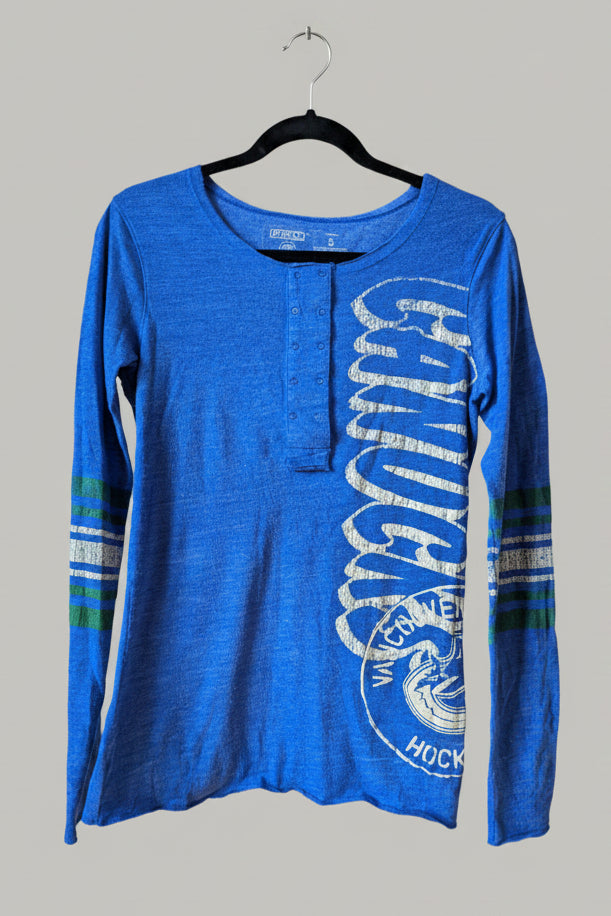 Close-up of the Vancouver Canucks graphic printed down the sleeve of the blue shirt.