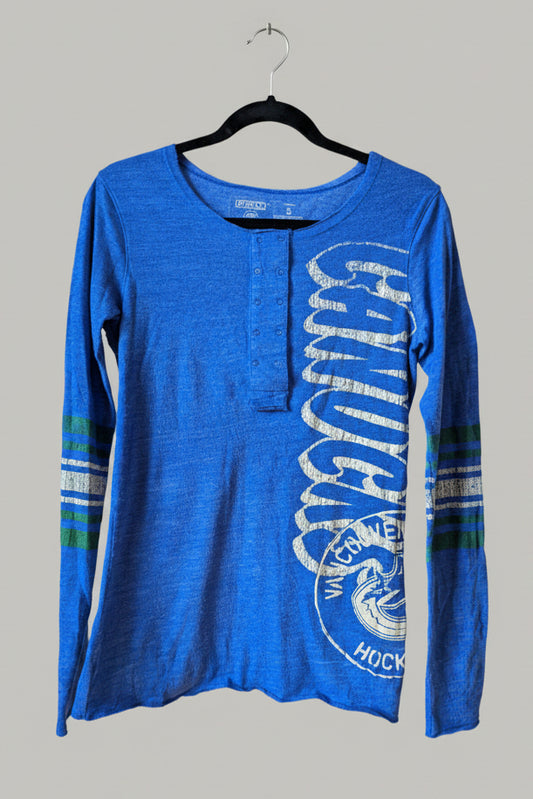 Close-up of the Vancouver Canucks graphic printed down the sleeve of the blue shirt.