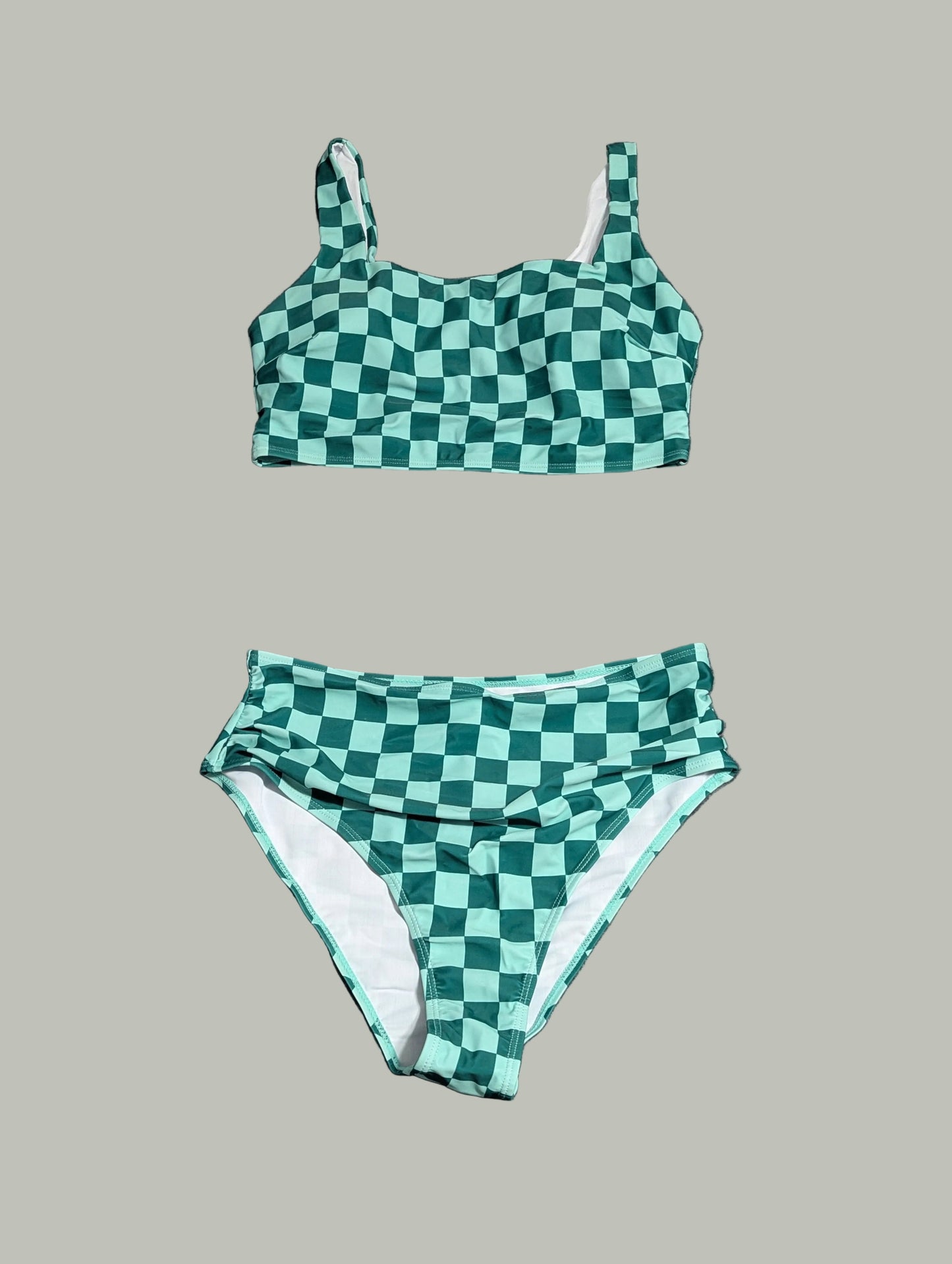 Front view of a curated thrift green and white checkered two-piece swimsuit with a cinched front detail on the bikini top, laid fla