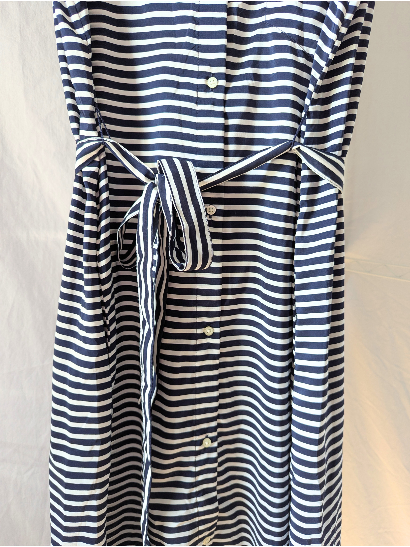 Close-up front view of a sleeveless blue and white striped Gap maxi dress, highlighting the clean white center buttons and matching fabric belt.