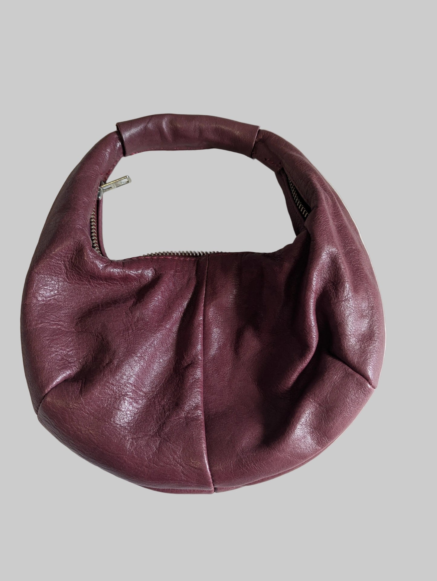Back view of a maroon genuine leather P'elle half-moon handbag with a shoulder strap.