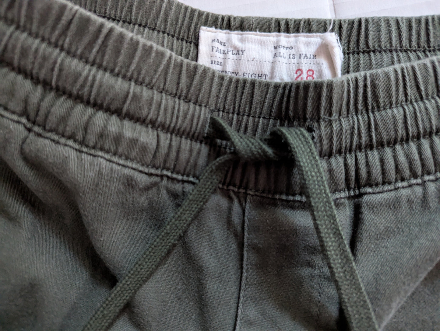 Close-up detail of the comfortable elastic waistband and stretch cotton twill fabric on the green Fairplay joggers.