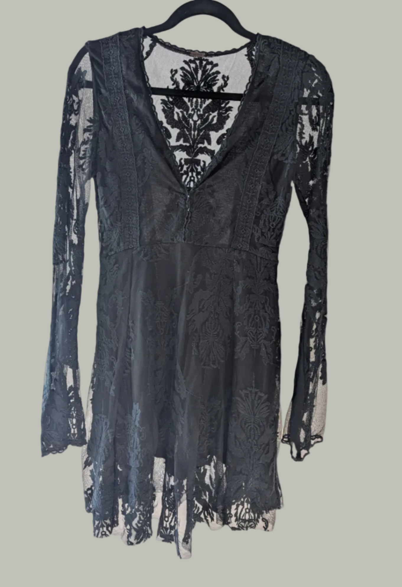 Front view of the black Free People lace mini dress showcasing the deep V-neckline hanging on a hanger