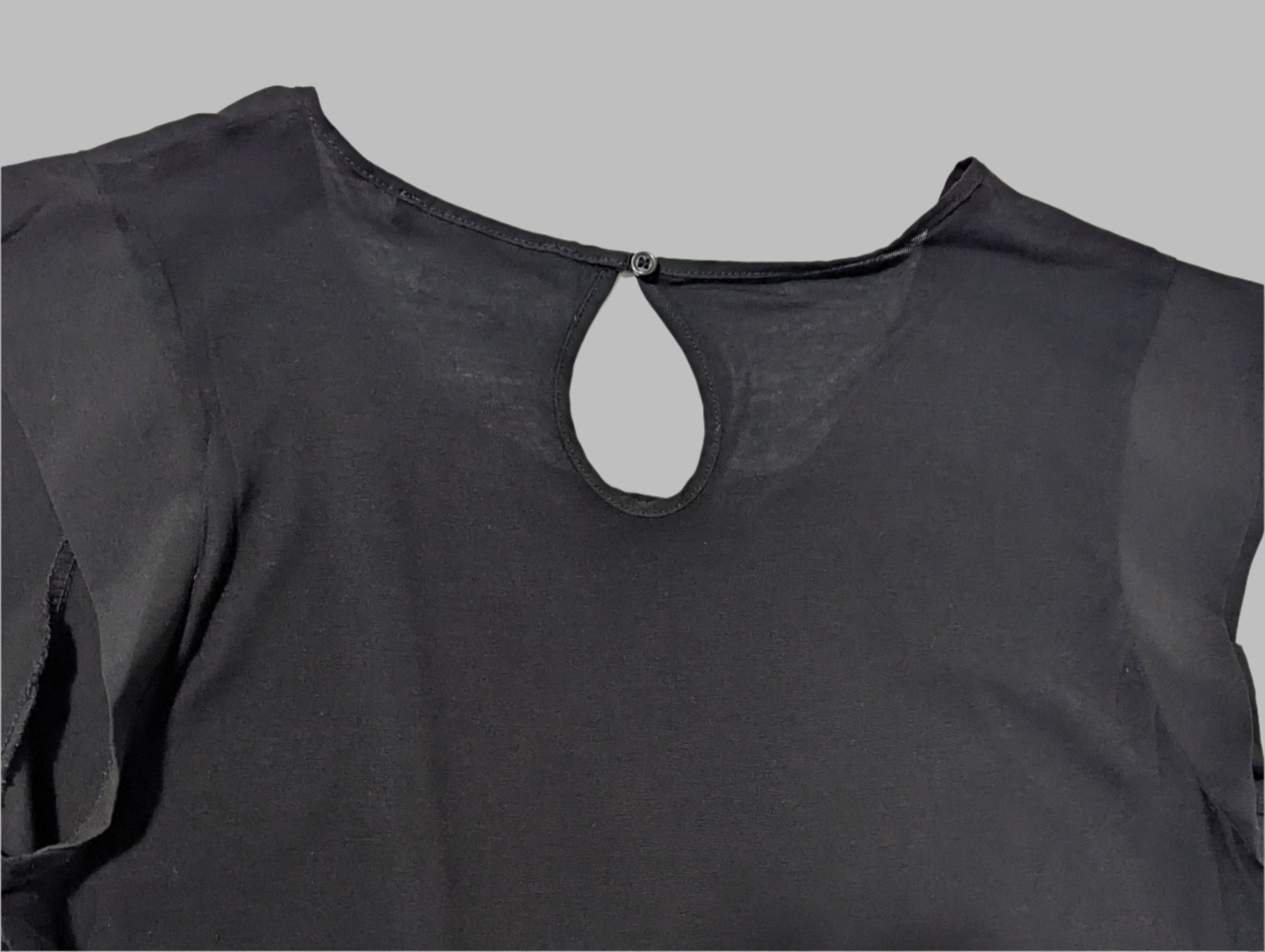 rear view of a black sleeveless French Connection blouse on a hanger featuring a round neck and elegant front keyhole cutout detail.