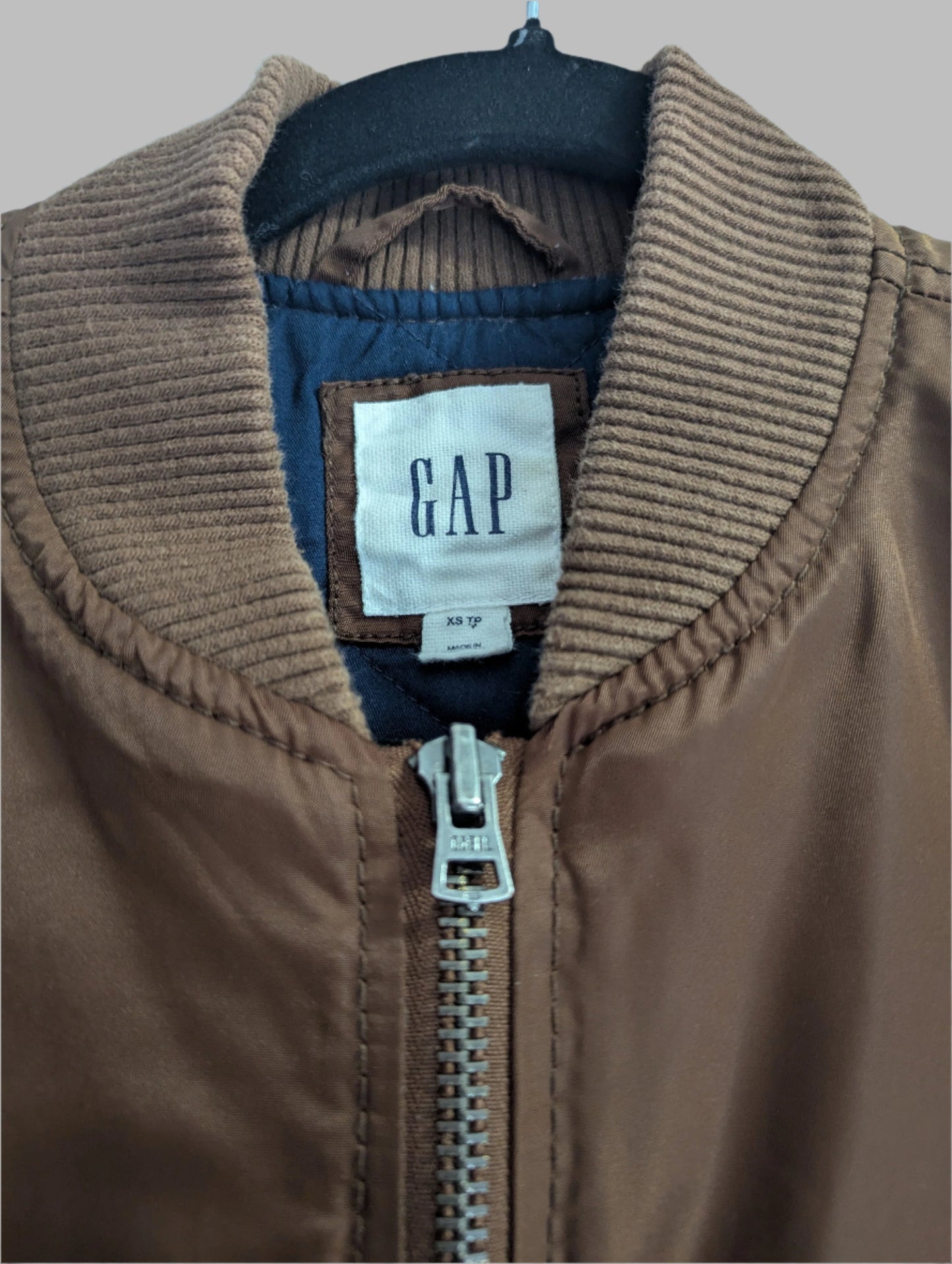Close-up detail of the inner blue Gap brand label, ribbed stand collar, and front zipper closure
