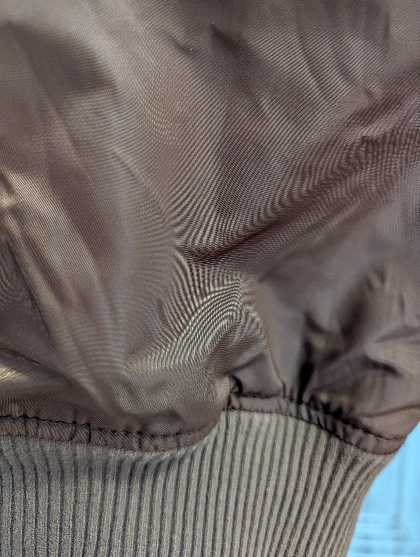 Detailed close-up view of the brown elastic rib-knit banded wrist cuff on the satin sleeve.