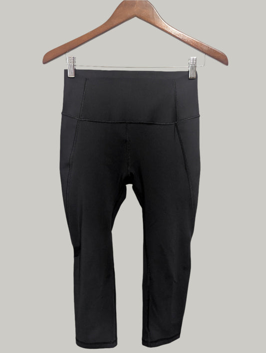 Front view of black high-rise Gap Fit compression cropped leggings hanging on a hanger.
