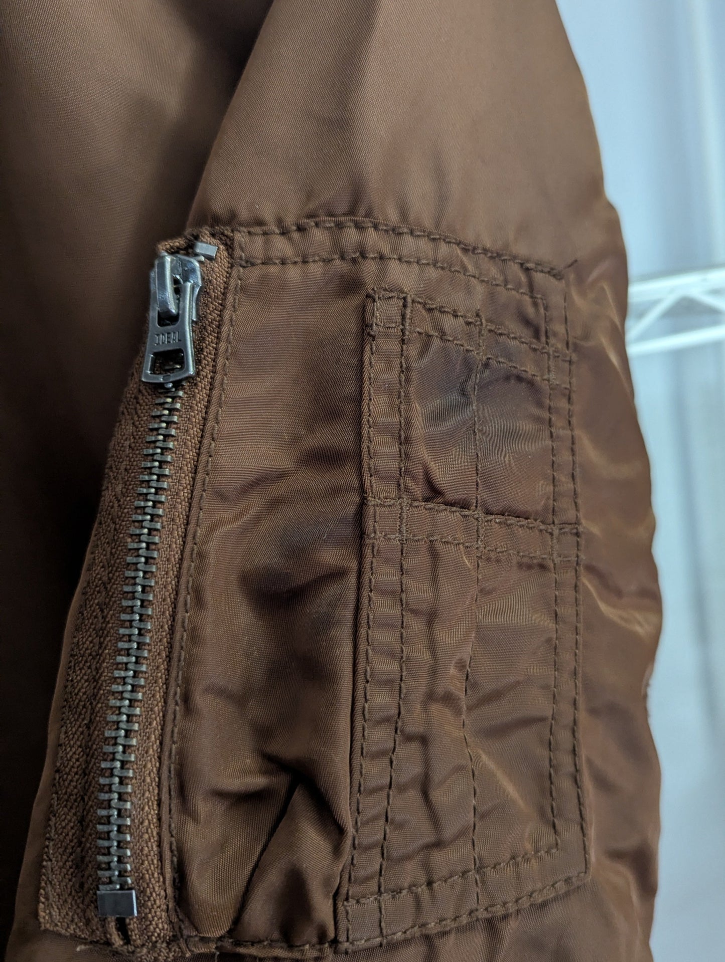 Close-up view of the side utility sleeve pocket showing minor authentic staining on the brown satin fabric.
