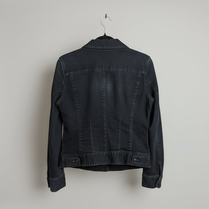 Rear view of a dark wash Gap deep indigo distressed denim trucker jacket with button-up closure and front pockets.