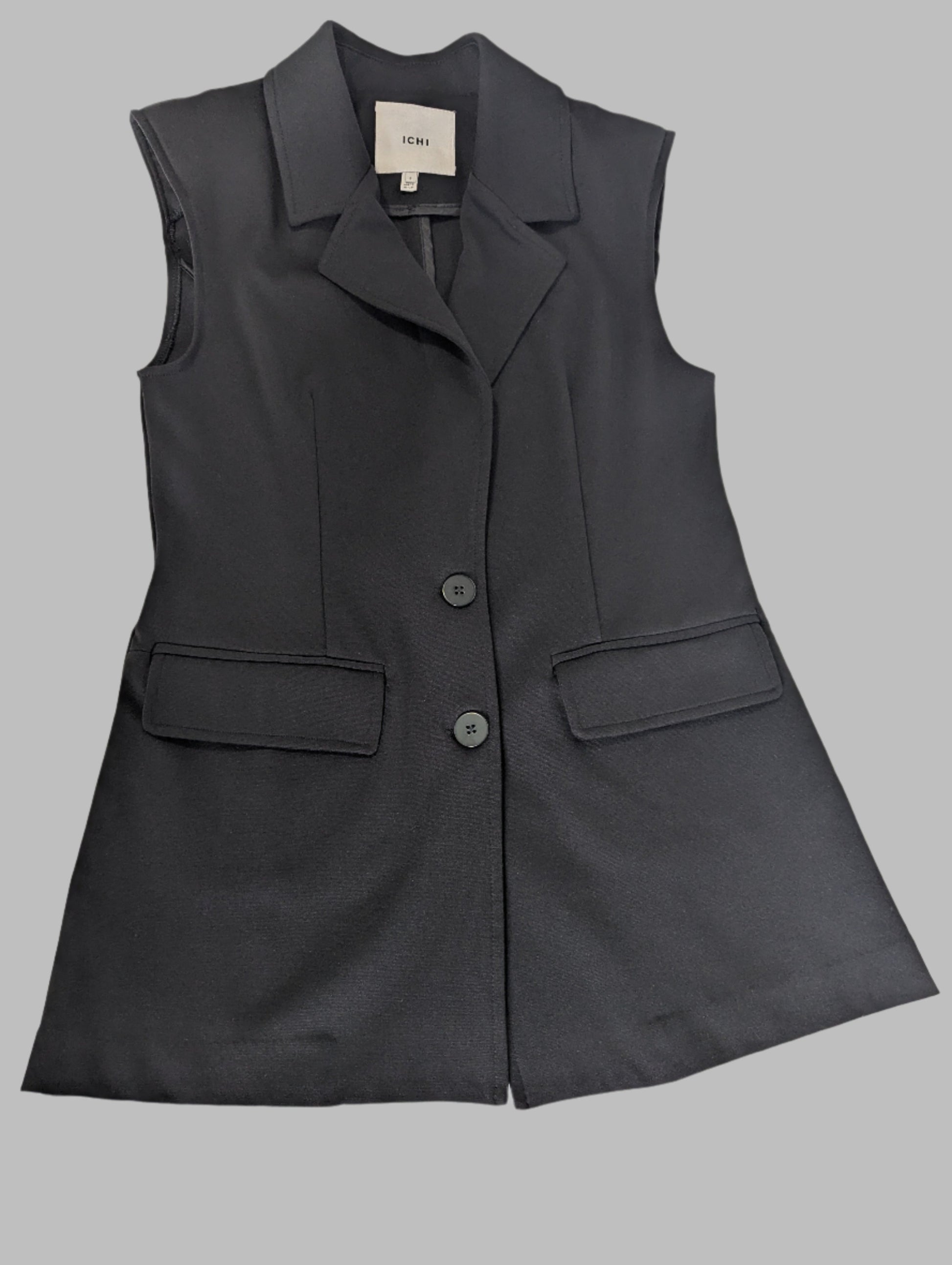 Front view of a structured black ICHI sleeveless blazer vest featuring a lapel collar and padded shoulders on a hanger.