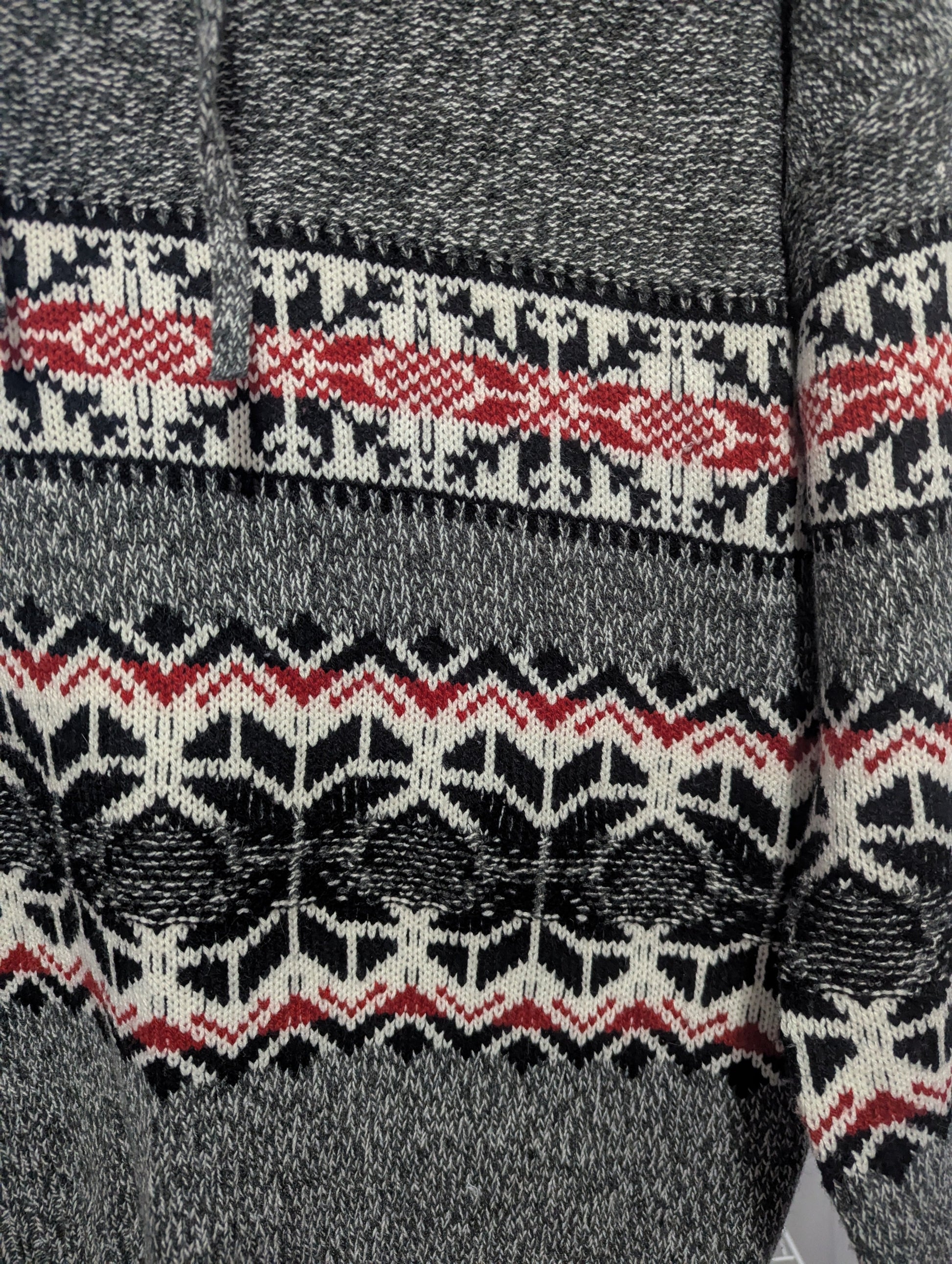 Close-up detail of the cozy acrylic-polyester blend knit texture and intricate snowflake pattern on the Kismet winter sweater.