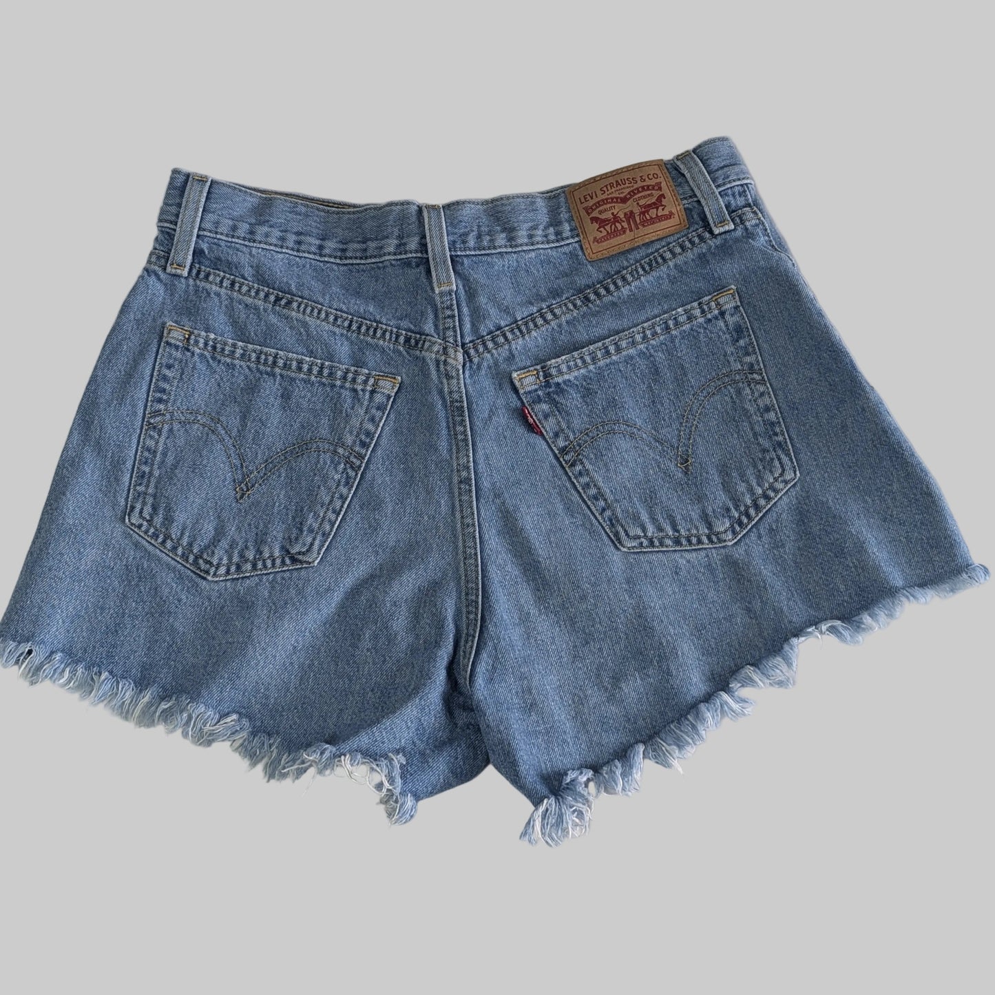 Back view of vintage Levi's high waisted denim shorts showing the classic pockets and distressed hem details.
