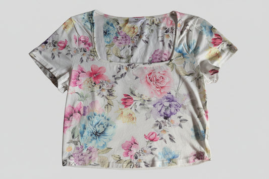 Front view of a white Live in The Moment short sleeve crop top baby tee featuring a colorful all-over pastel floral print.