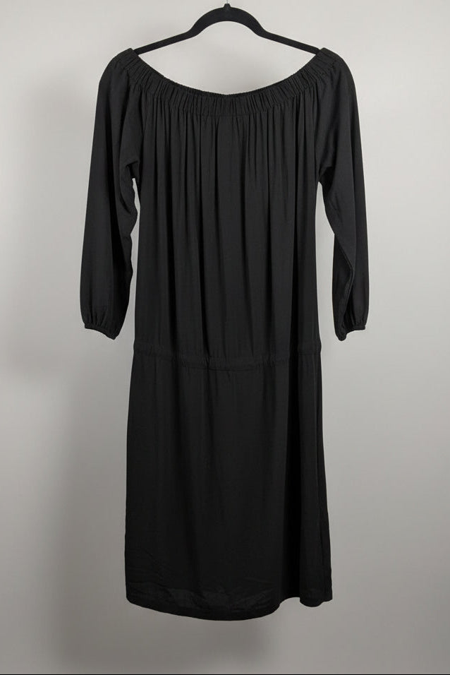 Back view of a black Lole Jamie off-the-shoulder midi dress with a tie waist hanging on a hanger against a gray background.
