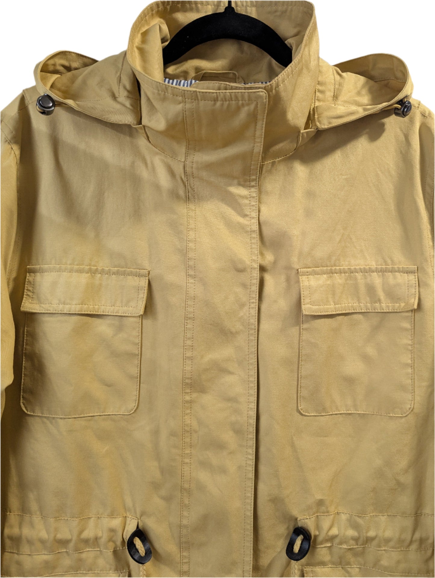 Close-up front view of a mustard yellow London Fog utility jacket, highlighting the collar, detachable hood, snap-button chest pockets, and bottom drawstring grommets