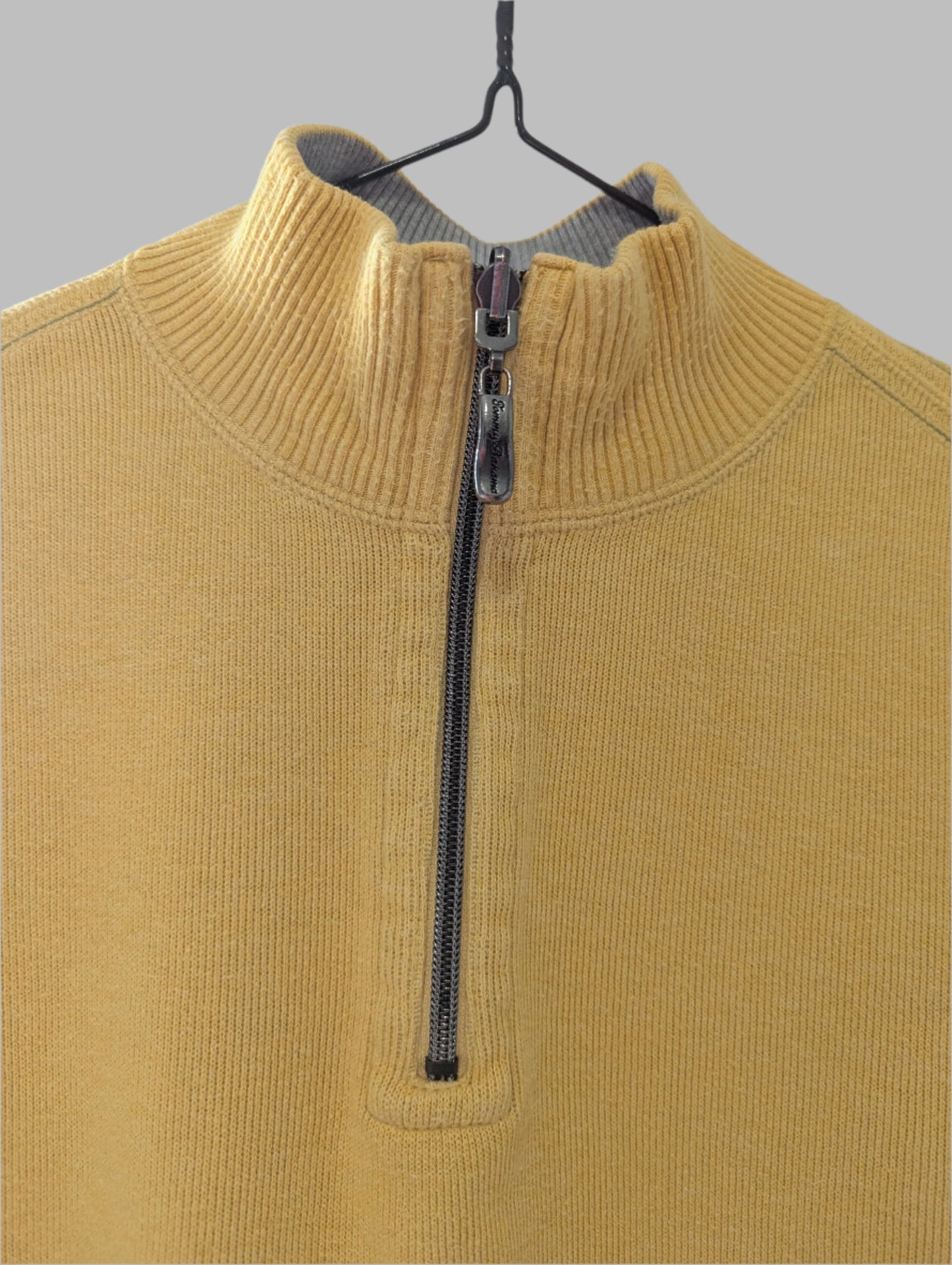 Front view of a men's yellow Tommy Bahama quarter-zip mock neck sweater hanging on a hanger