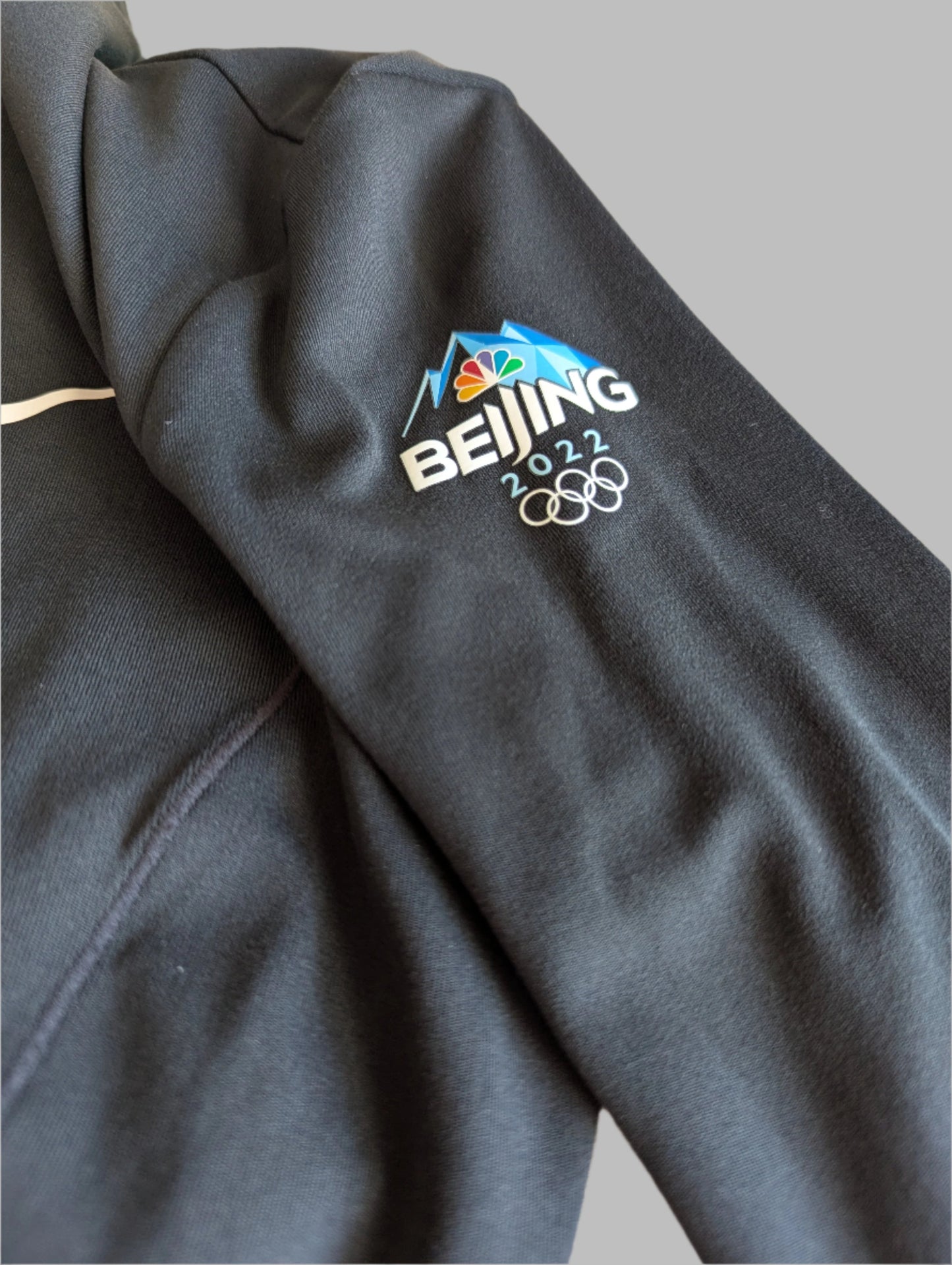 Sleeve detail of beijing 2022 olypics on a black Nike Yoga Dri-Fit full zip athletic jacket 