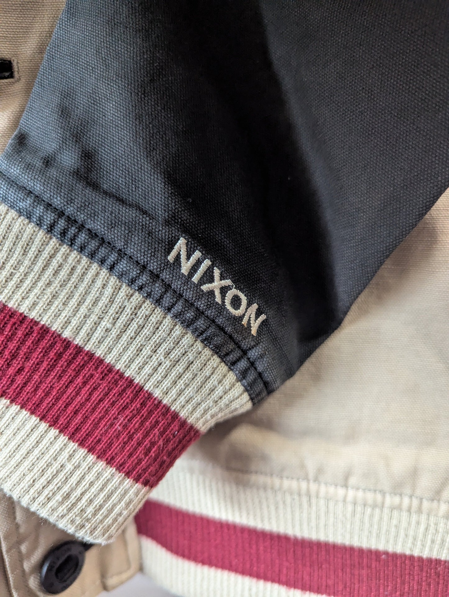 Detailed view of the 100% breathable cotton fabric and striped elastic knit wrist cuffs on the varsity jacket.