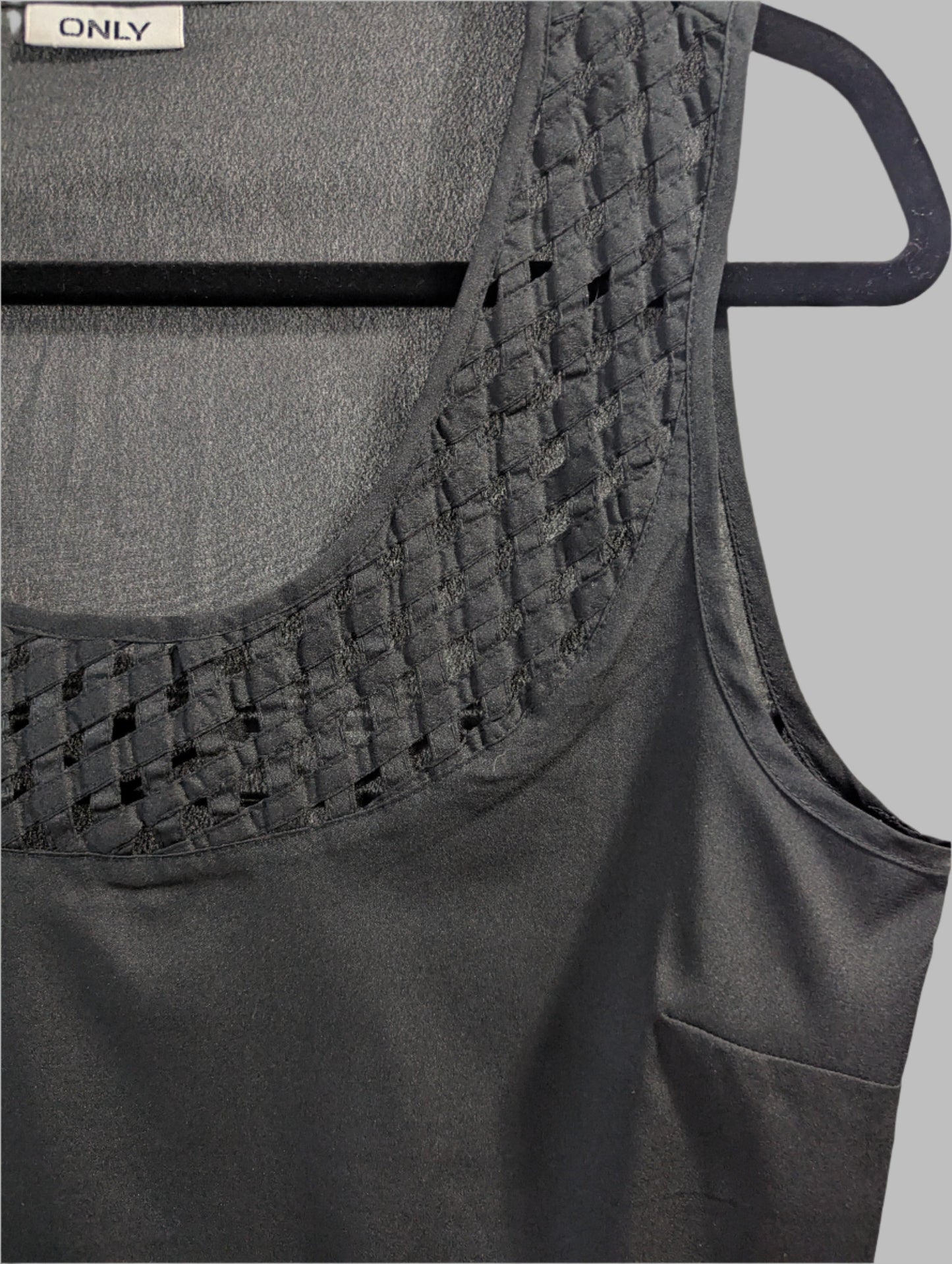 Close up view of a black sleeveless ONLY tank top featuring an intricate geometric laser cutout design across the chest.