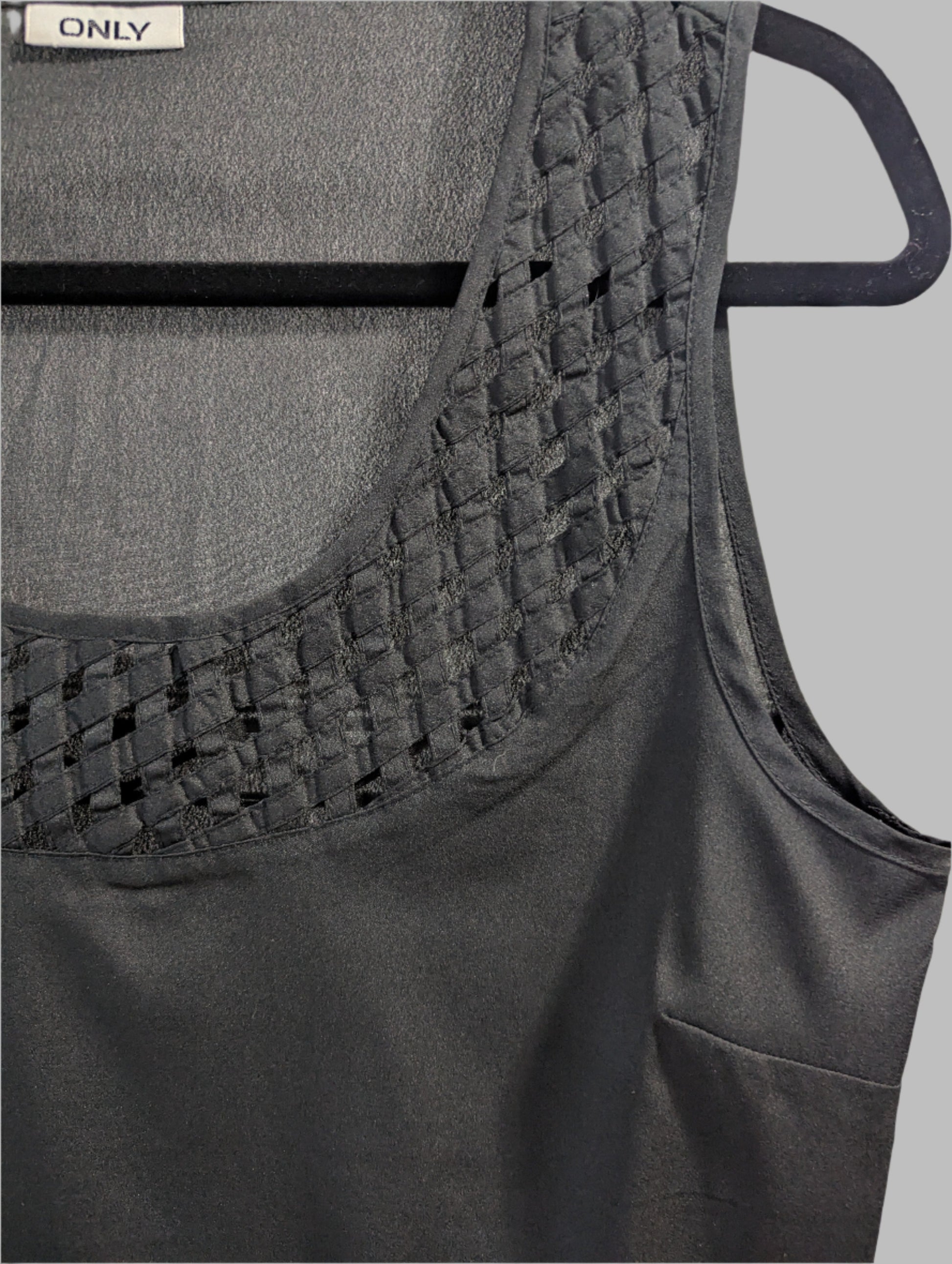 Close up view of a black sleeveless ONLY tank top featuring an intricate geometric laser cutout design across the chest.