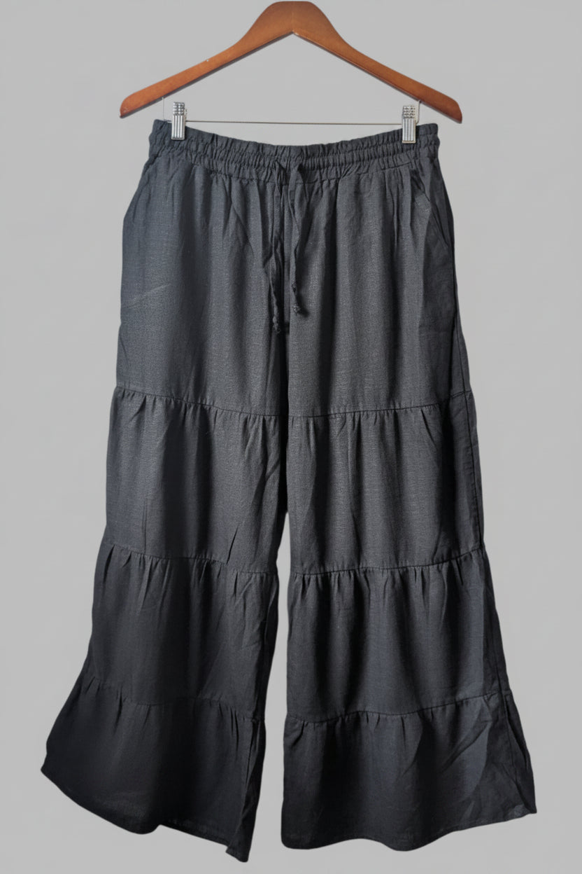 Front view of black Papillon linen-blend wide leg pants with an elastic tie waistband hanging on a wooden hanger.