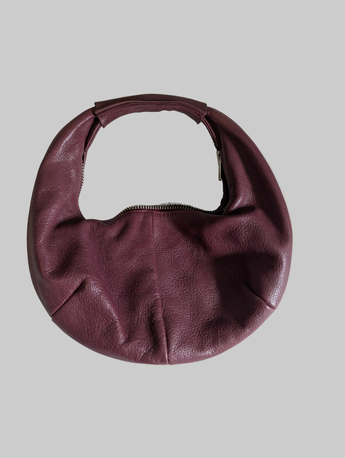 Front view of a maroon genuine leather P'elle half-moon handbag with a shoulder strap.