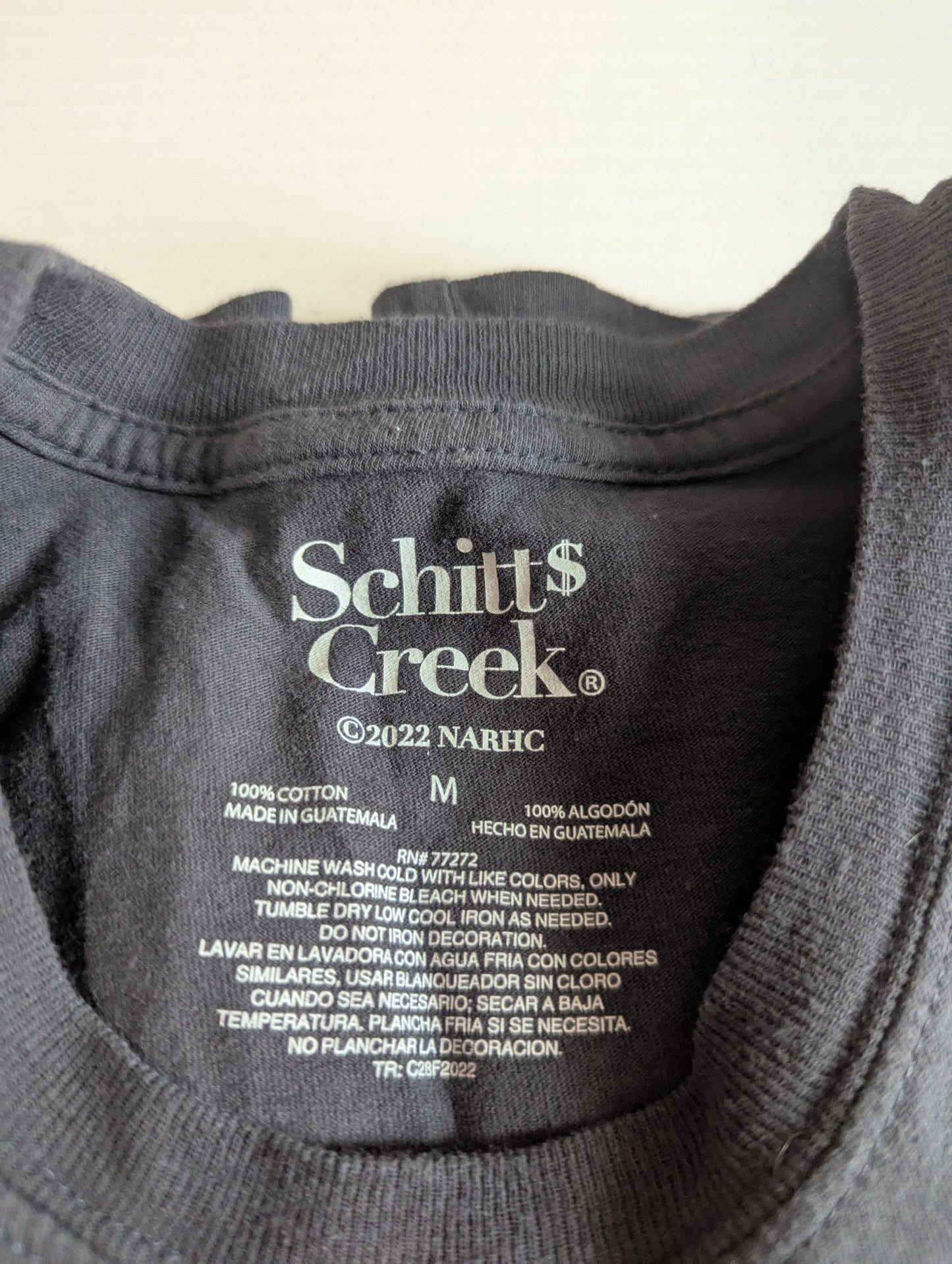Close-up detail of the authentic inner neck printed Schitt's Creek official merchandise logo and size medium stamp.