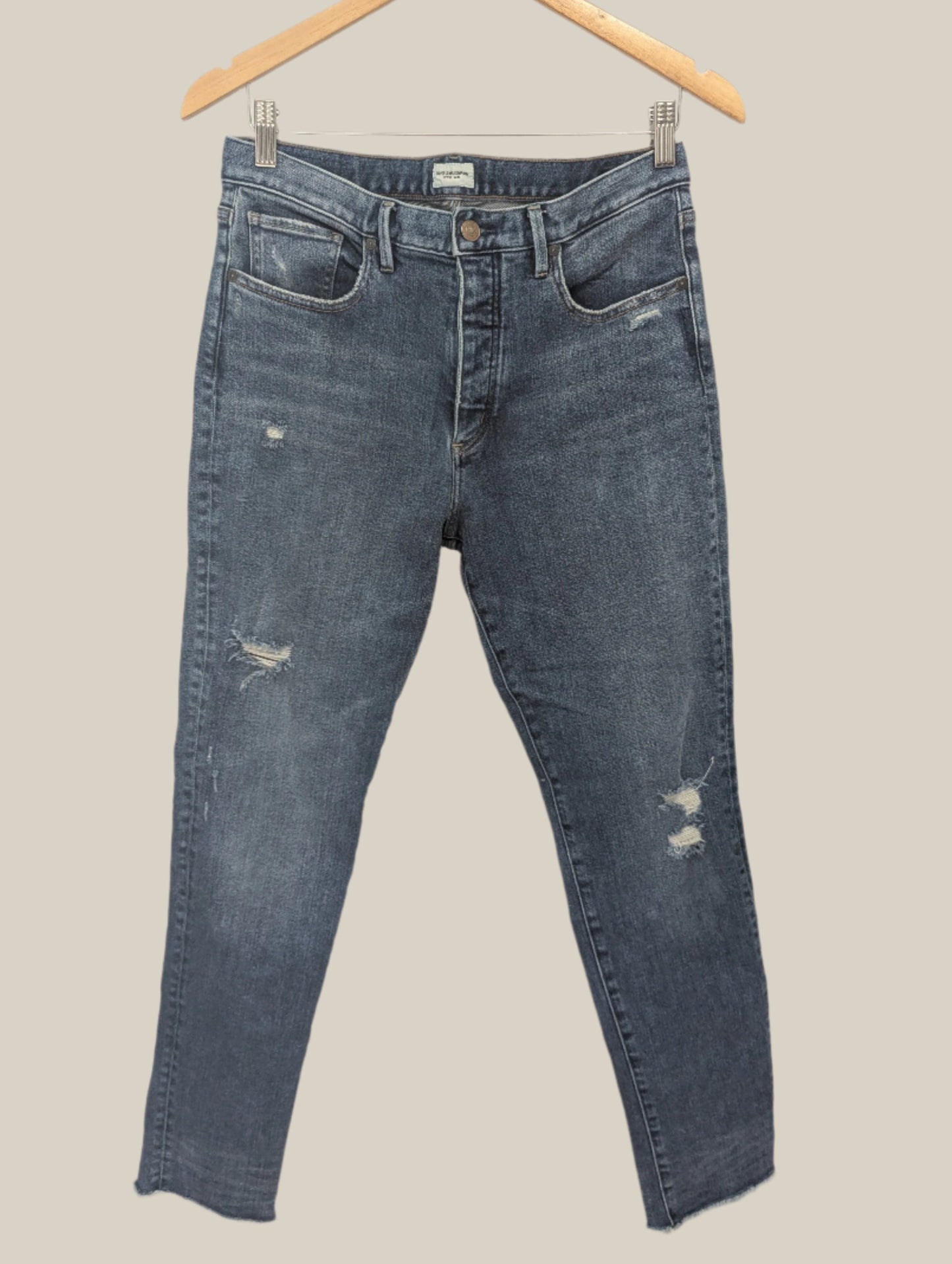 Front view of women's Silver Jeans Maryland high waisted distressed blue jeans hanging on a hanger.