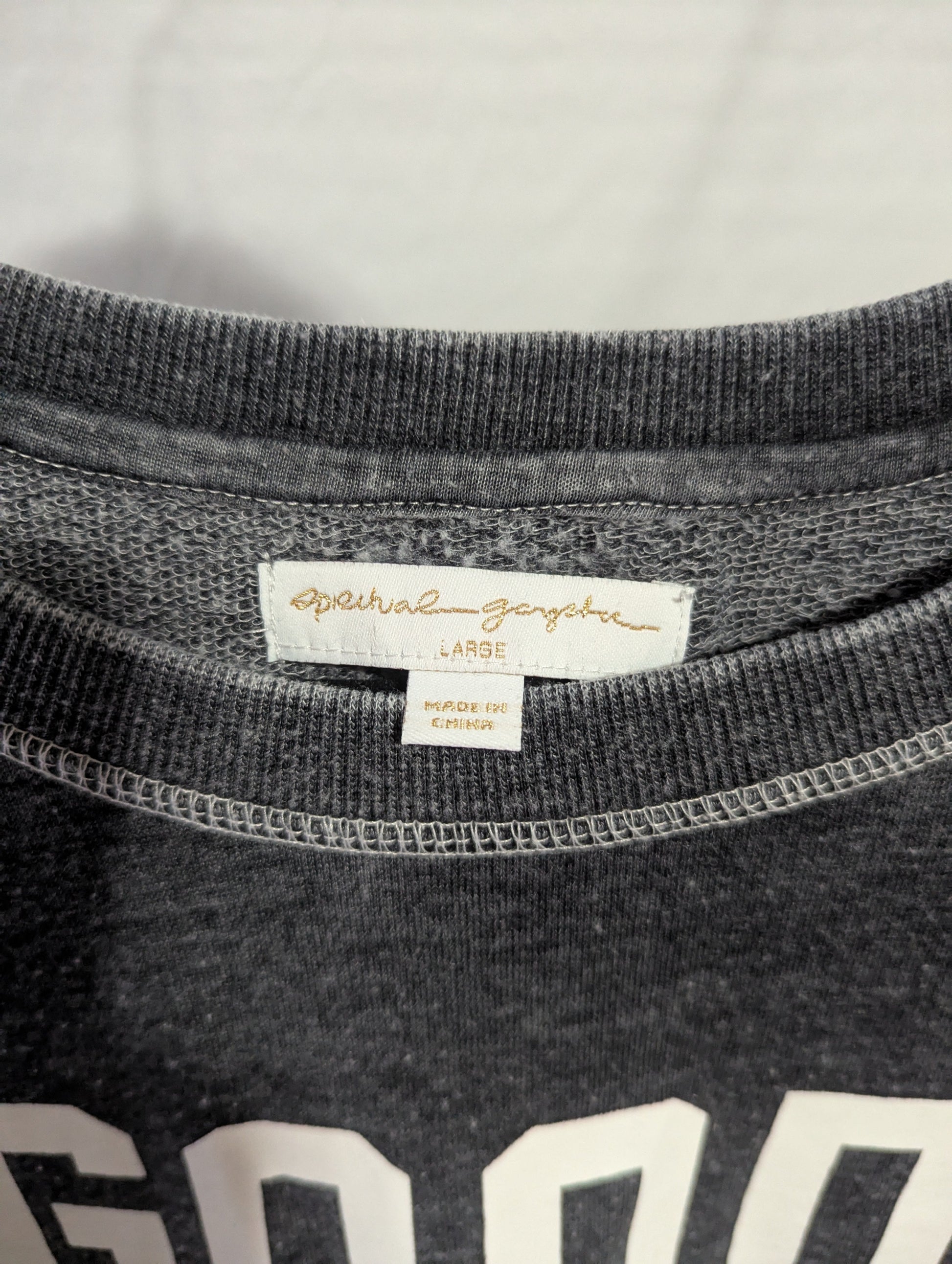 Close-up detail of the crew neckline and authentic interior Spiritual Gangster brand logo label inside the collar